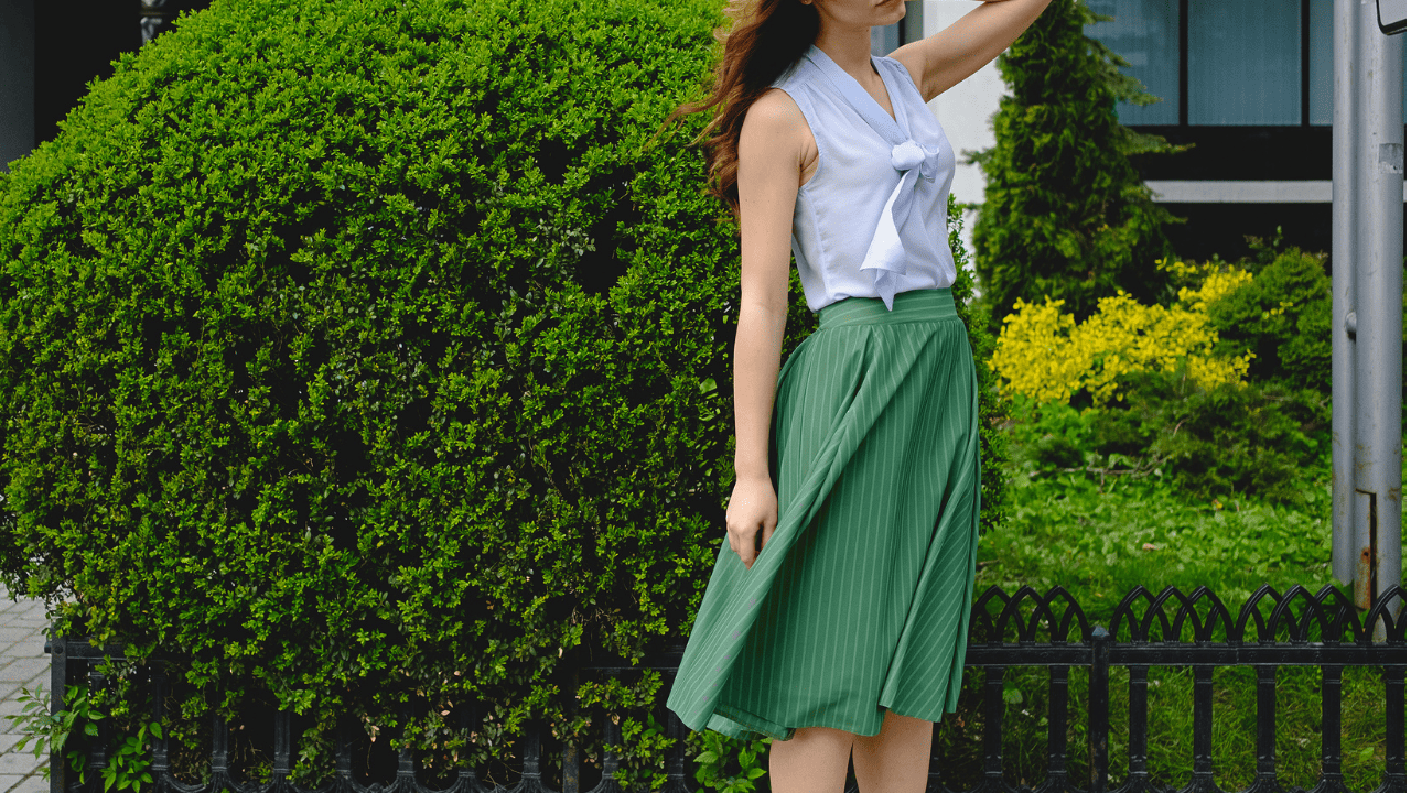 Mulher utilizando blusa branca e saia godê verde.