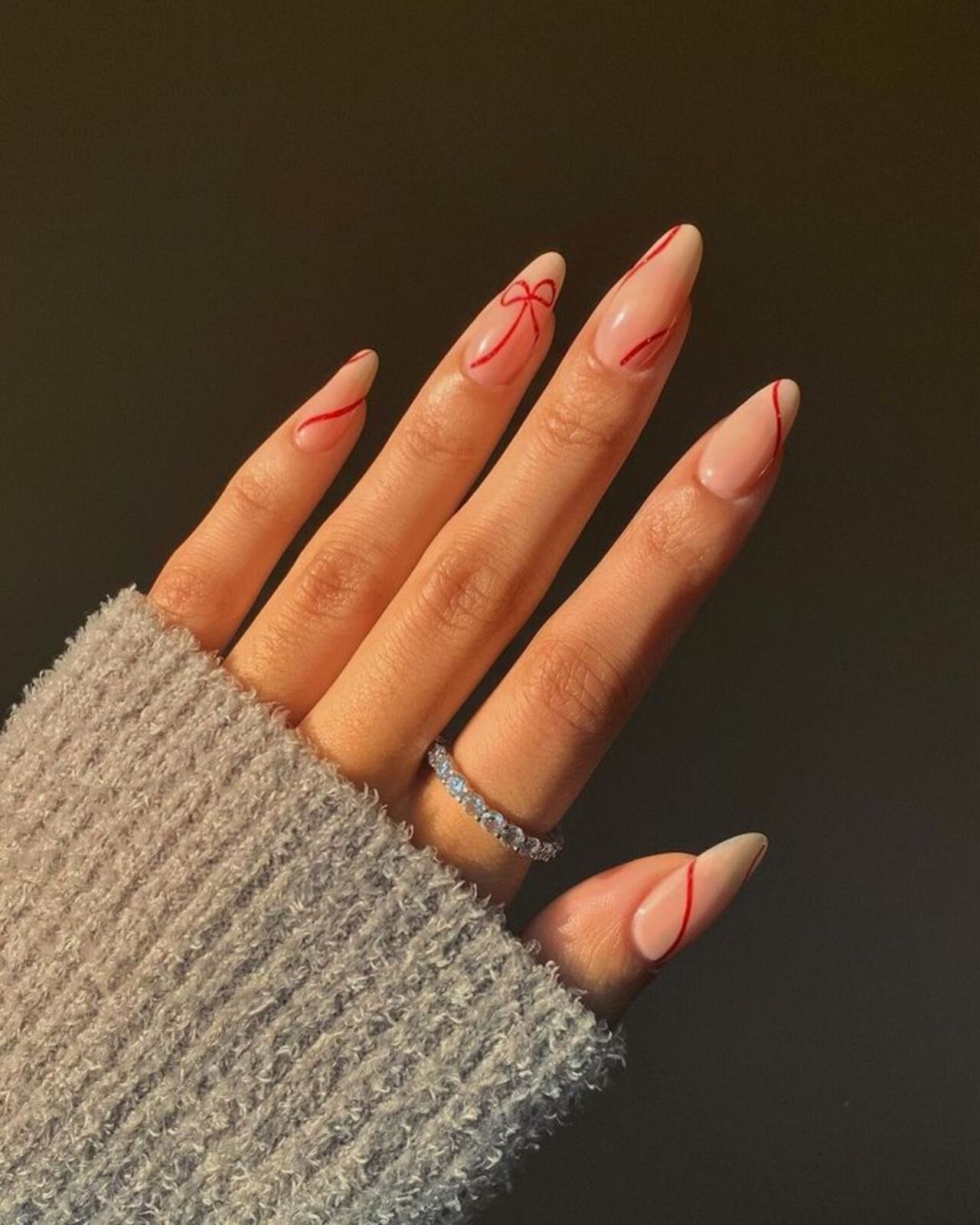 Um 'lacinho' e linhas vermelhas levam romance às unhas de forma sutil