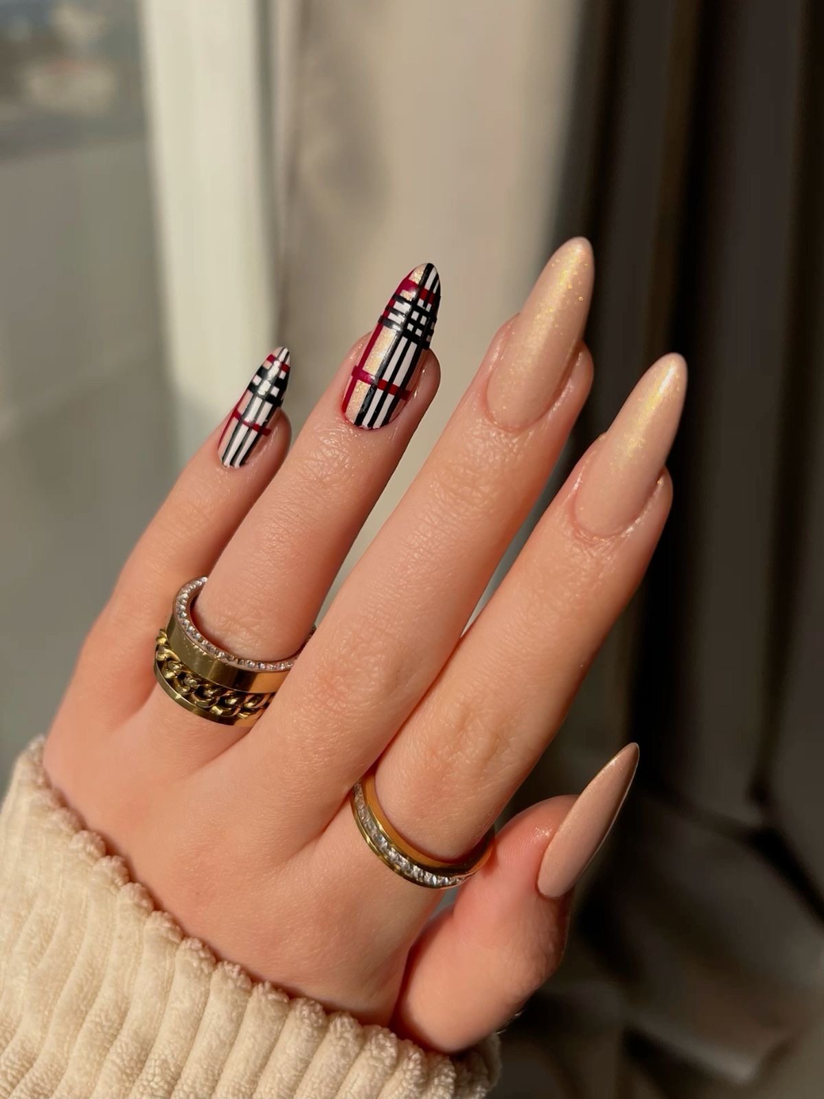 Imagem de mão exibindo unhas com estampa xadrez e brilho.
