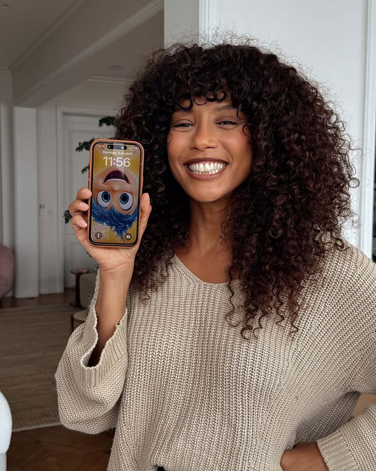 Imagem de mulher negra sorrindo com cabelos cacheados e franja.