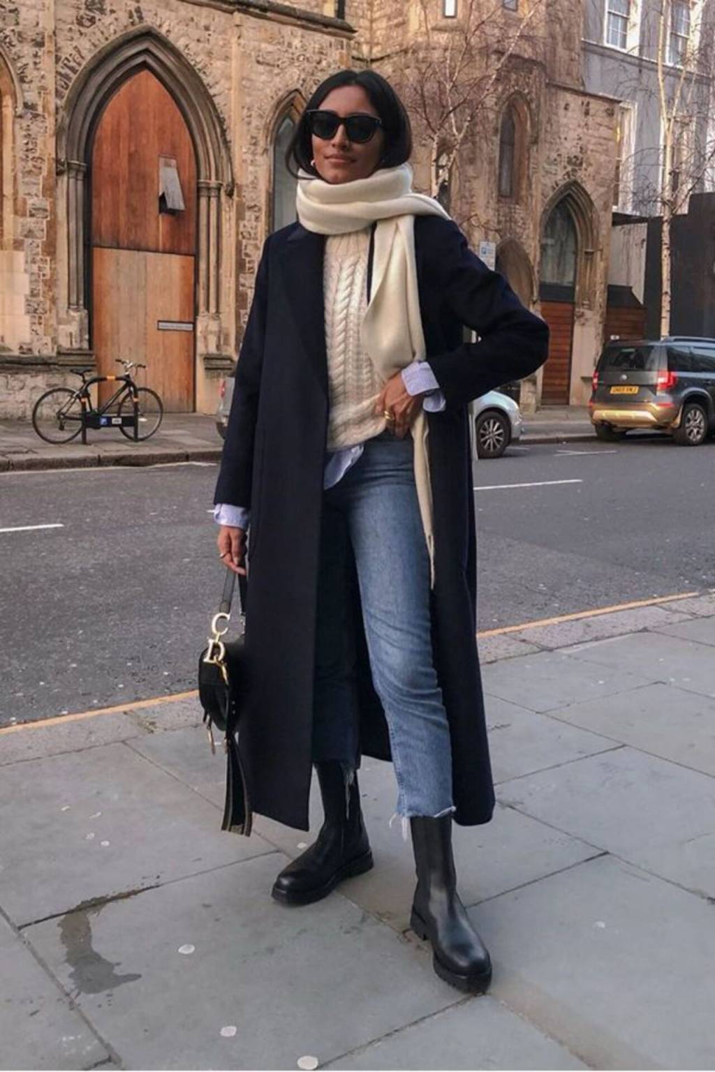 sobretudo-cachecol Imagem de mulher pousando para foto com look com calça jeans, sobretudo preto e cachecol bege.