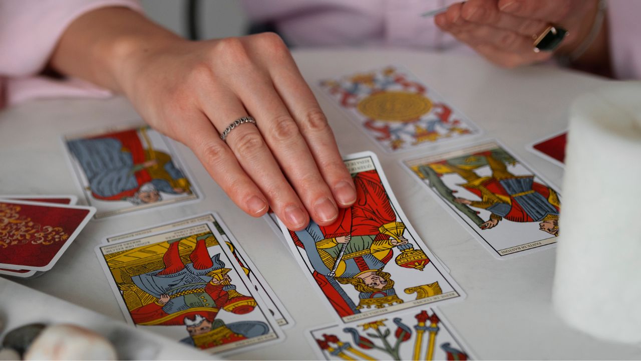 Mão feminina tirando cartas de tarô para o mês de julho