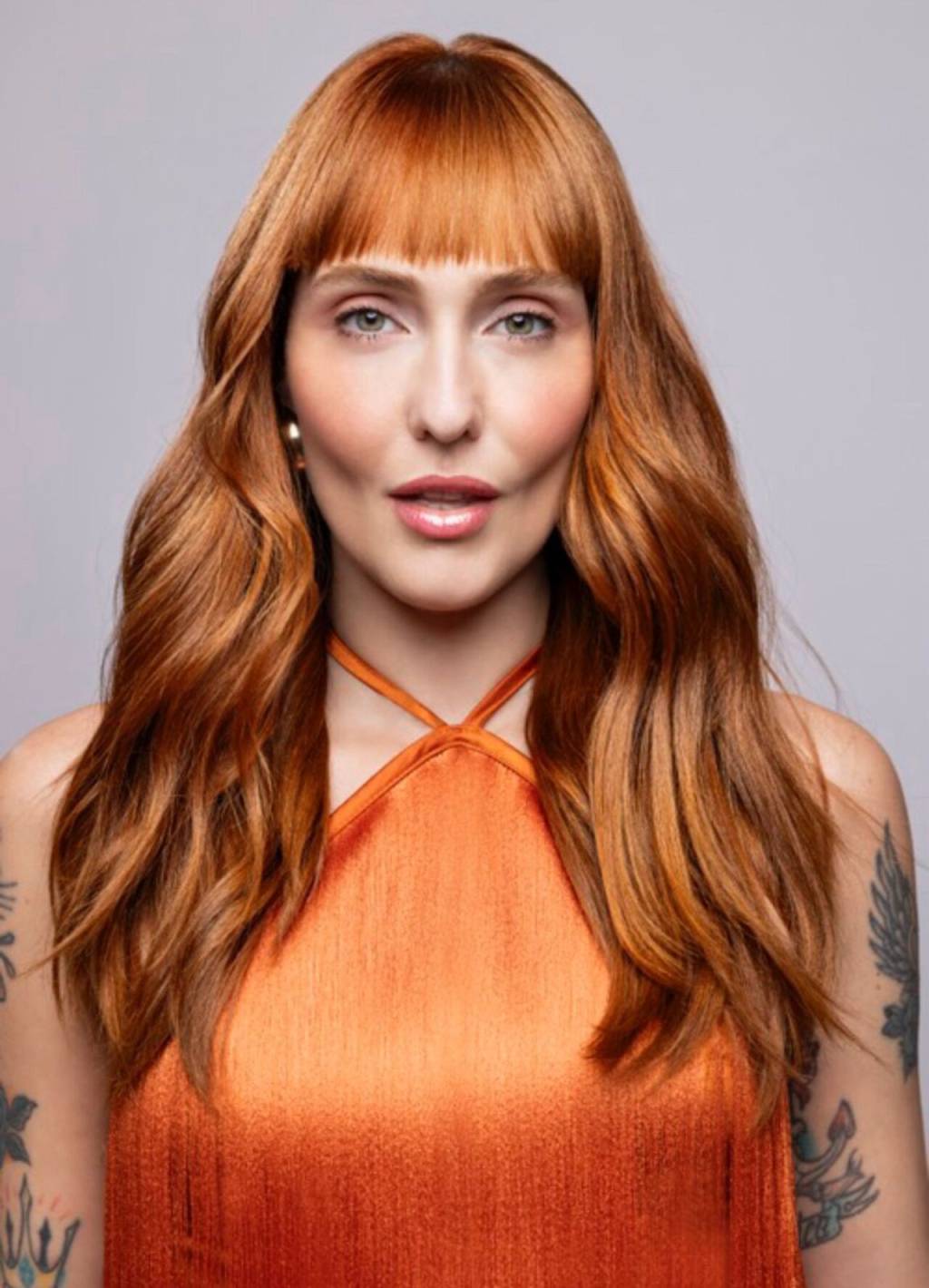 tons-cabelo-inverno (3) Imagem de mulher com cabelos ruivos alaranjados, franja e camiseta laranja.