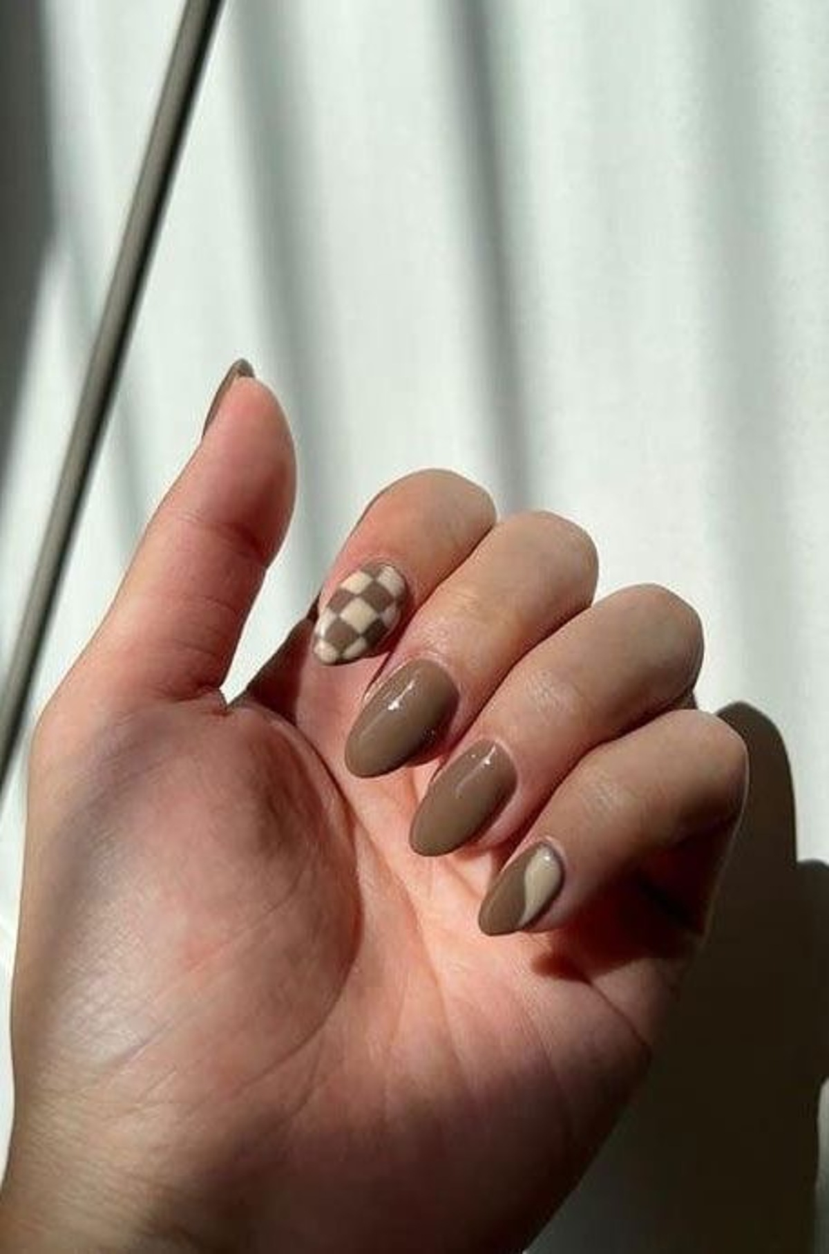 Imagem de mão exibindo unhas em moccha mousse com decoração xadrez.
