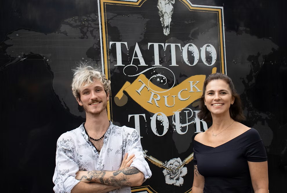 Imagem de mãe e filho a frente do caminhão que abriga o projeto Tattoo Truck