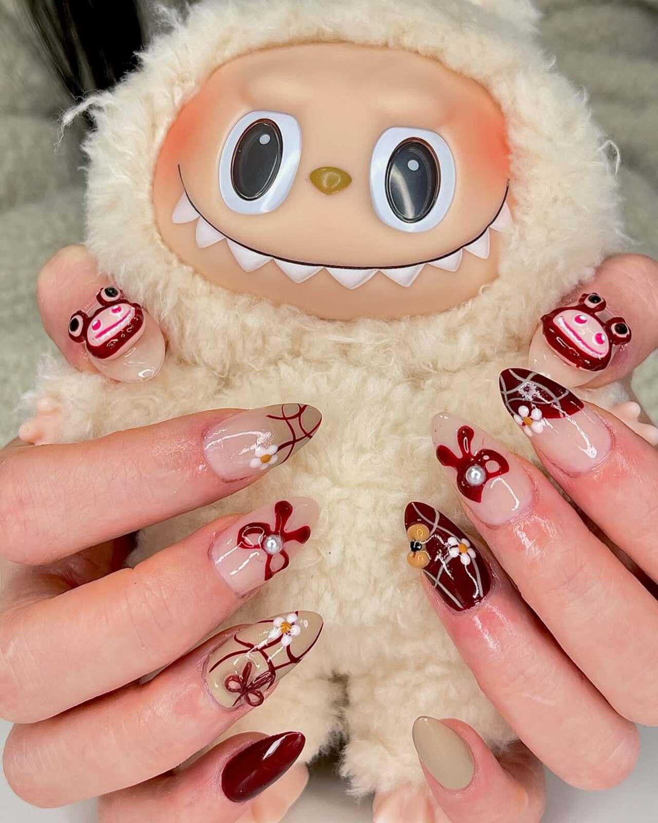 Imagem mostra nail art de labubu vinho.