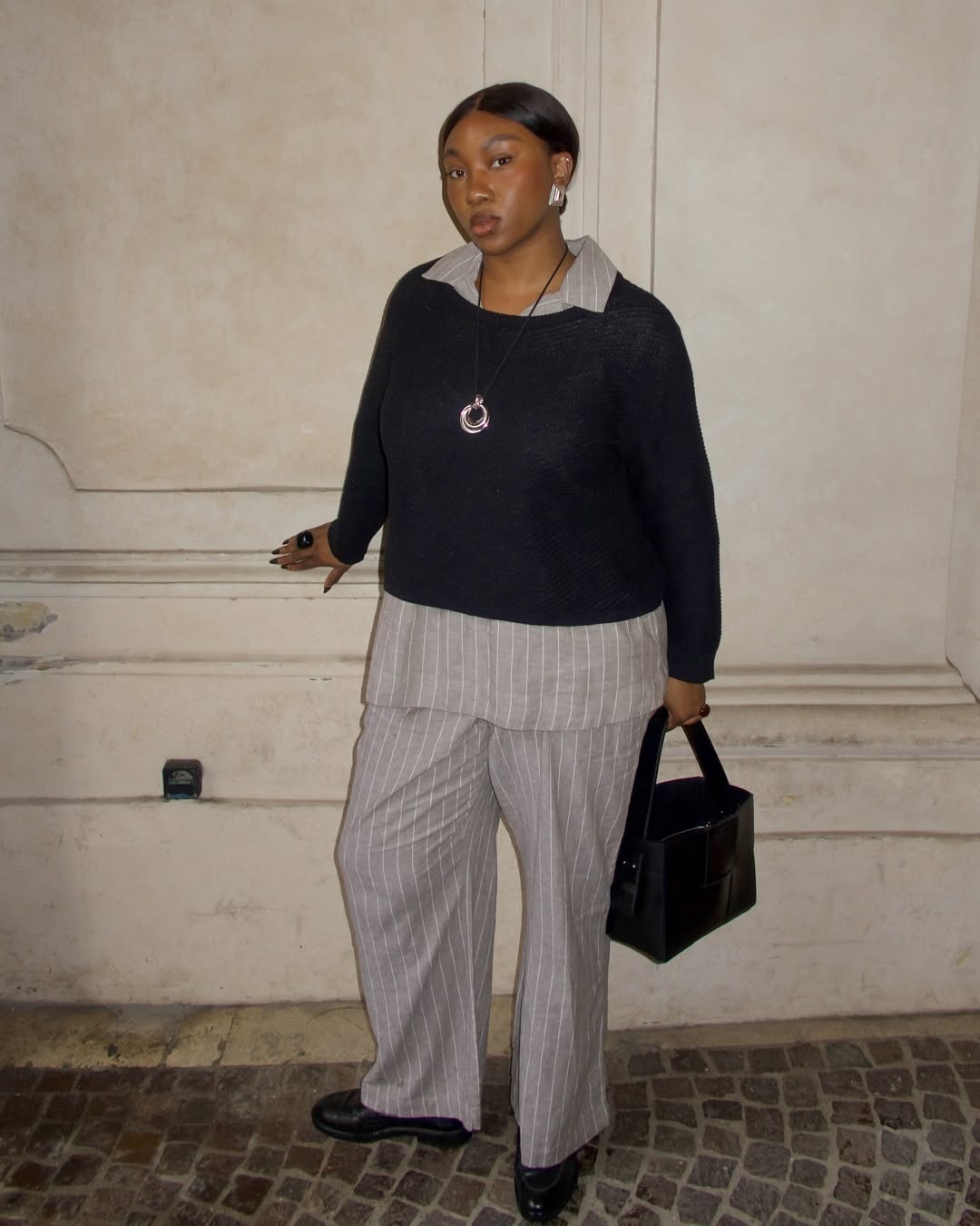 Look neutro com sobreposição de suéter e camisa listrada