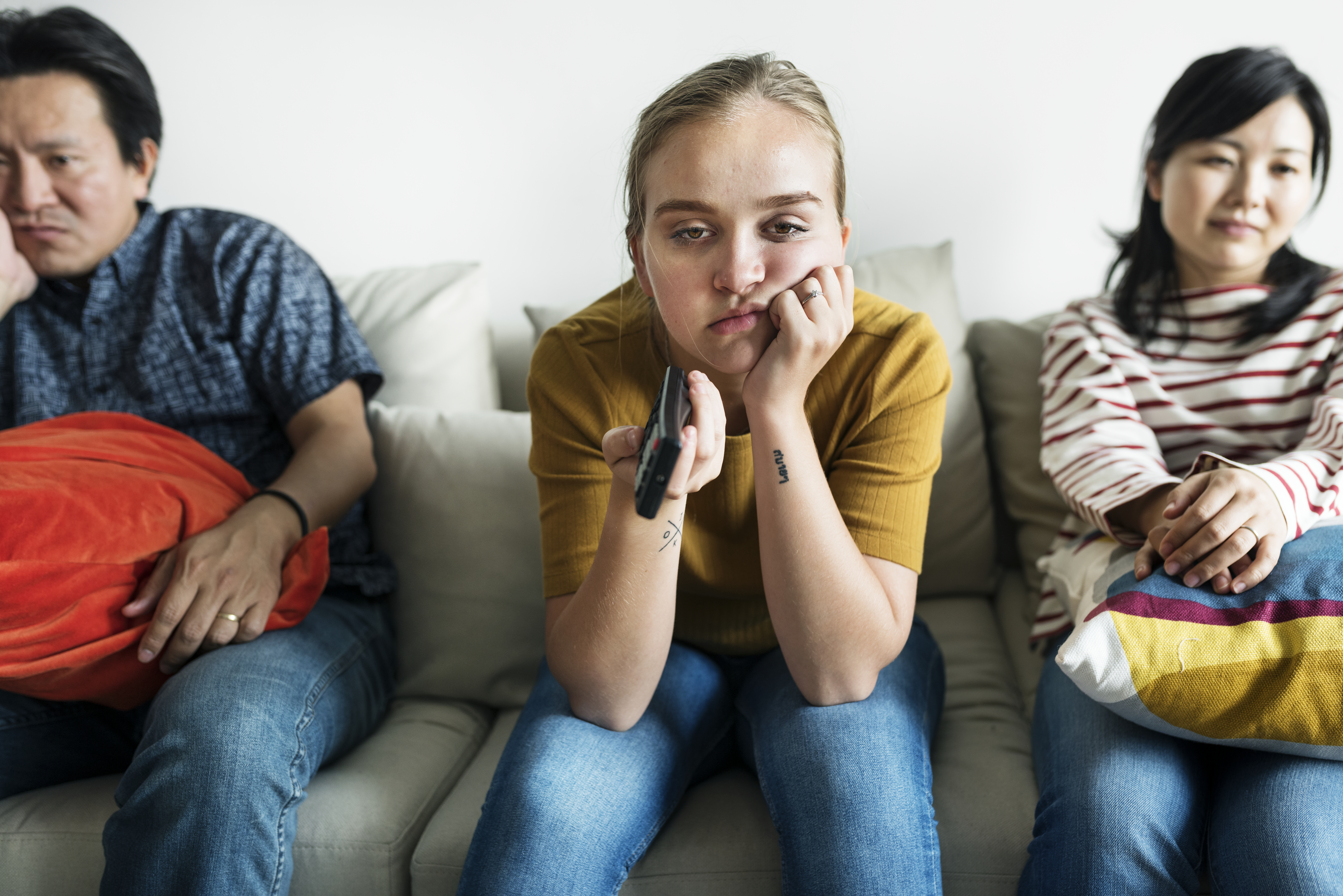 Imagem de família vendo TV, desanimada e distantes emocionalmente.