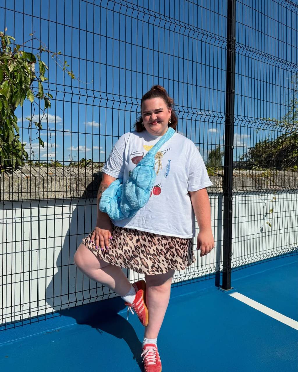 saia-e-camiseta-divertida Look plus size com saia animal print, camiseta branca e tênis vermelho