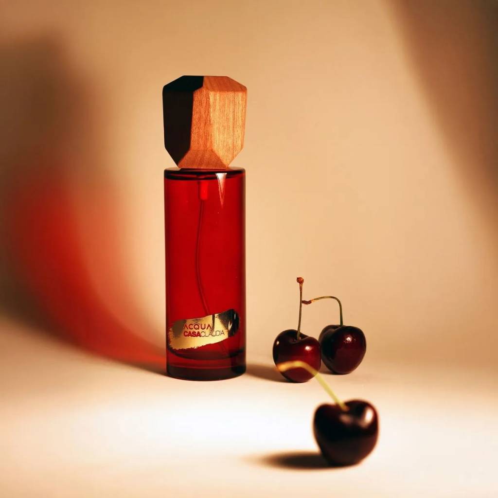 Imagem de embalagem de perfume para a casa rodeado de cerejas de acqua aroma