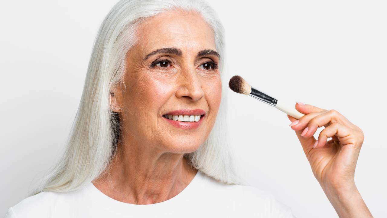 Foto de uma mulher com pele madura passando maquiagem