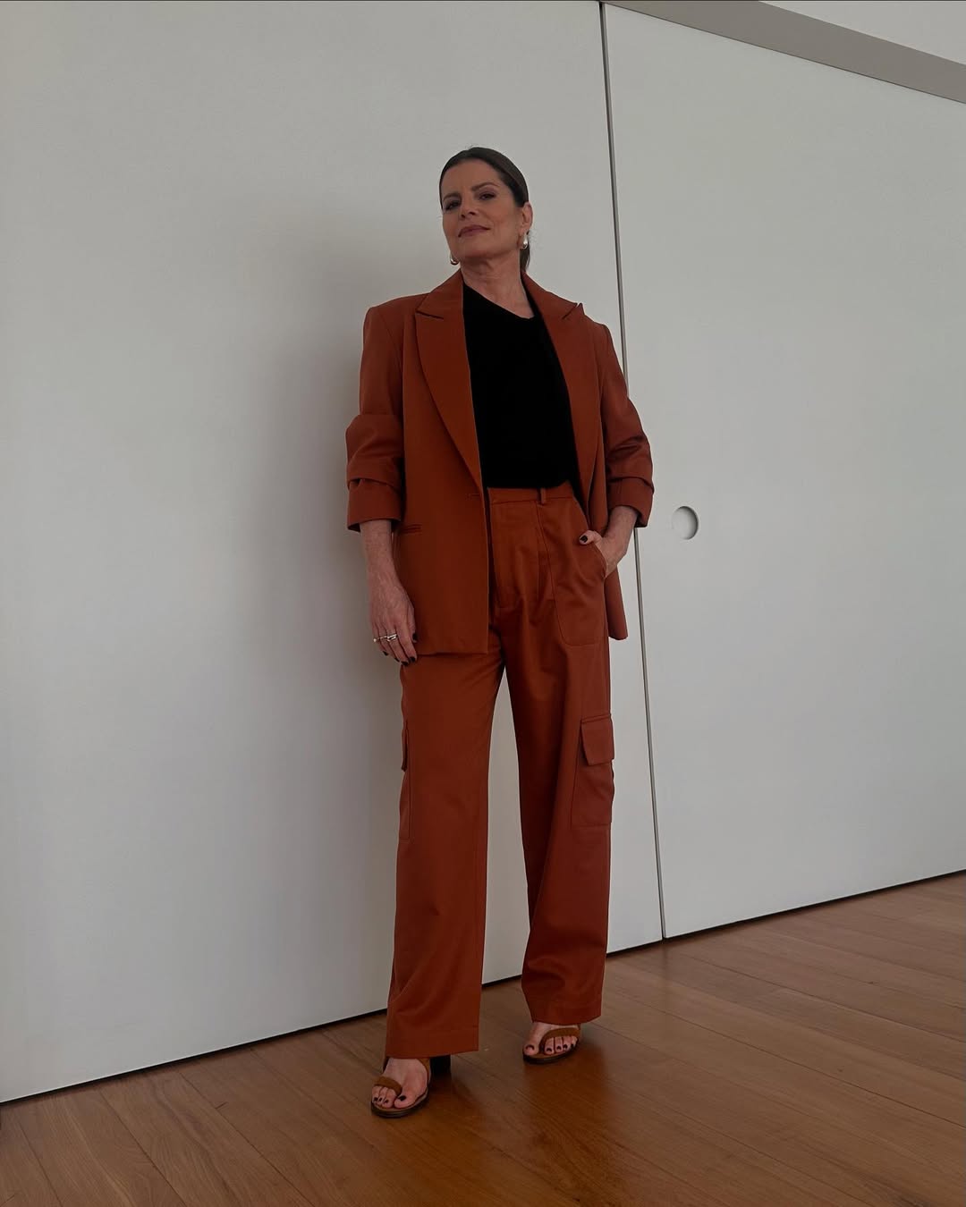 Foto de Debora Bloch usando um look composto por conjuntinho de blazer e calça vermelho, além de blusa preta e salto preto