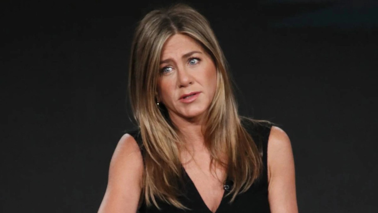 Jennifer Aniston, com expressão séria, durante entrevista em que comenta sobre suas tentativas de engravidar e os julgamentos que enfrentou ao longo da carreira.