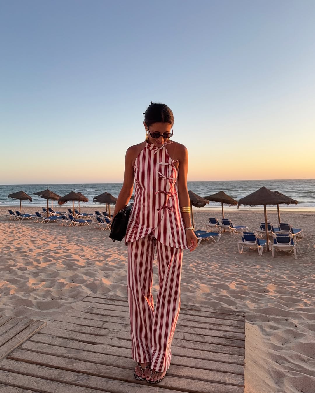 Foto de uma mulher usando um look composto por conjunto de regata e calça listradas vermelha