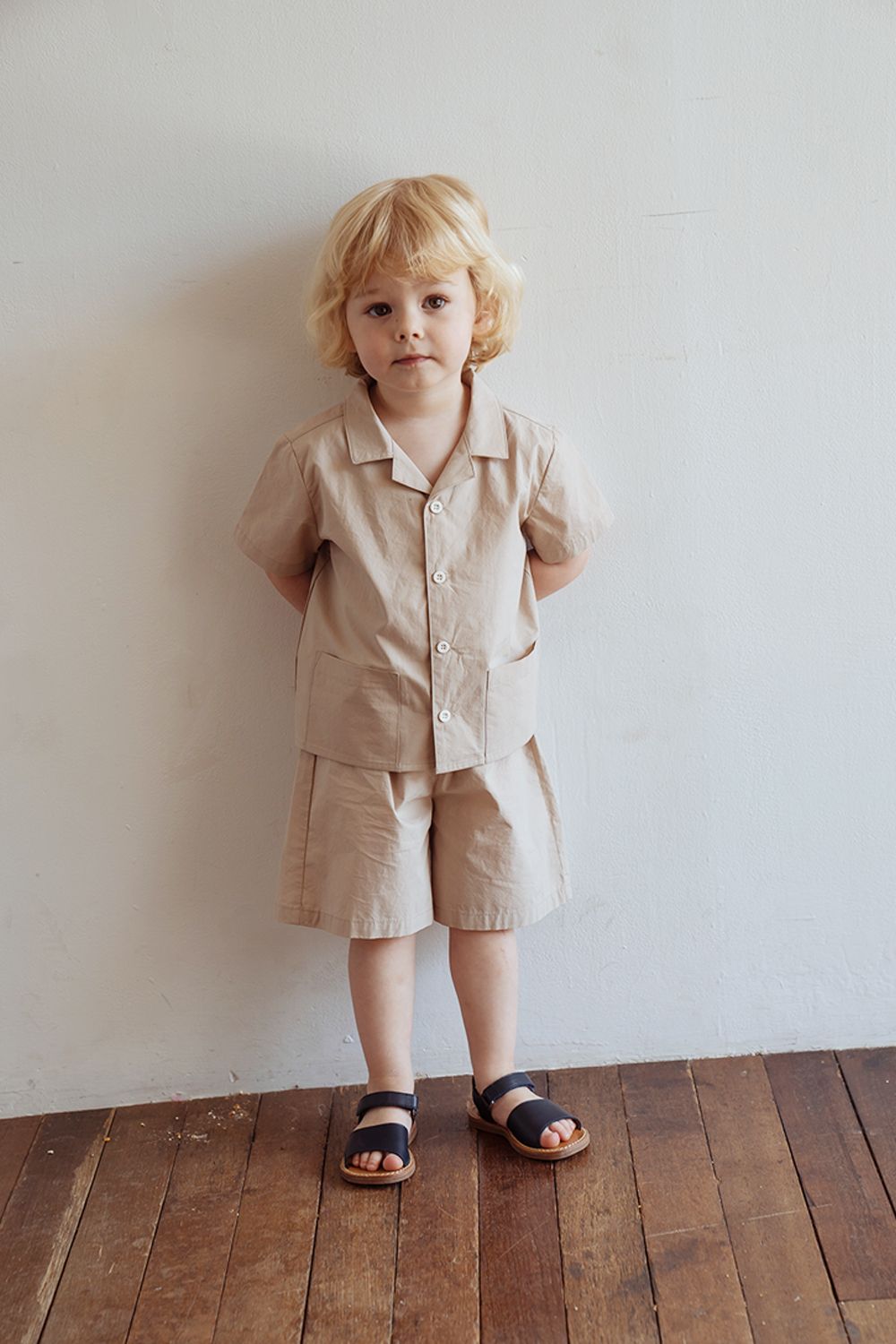 Foto de um menino usando um look composto por camisa, bermuda e papete