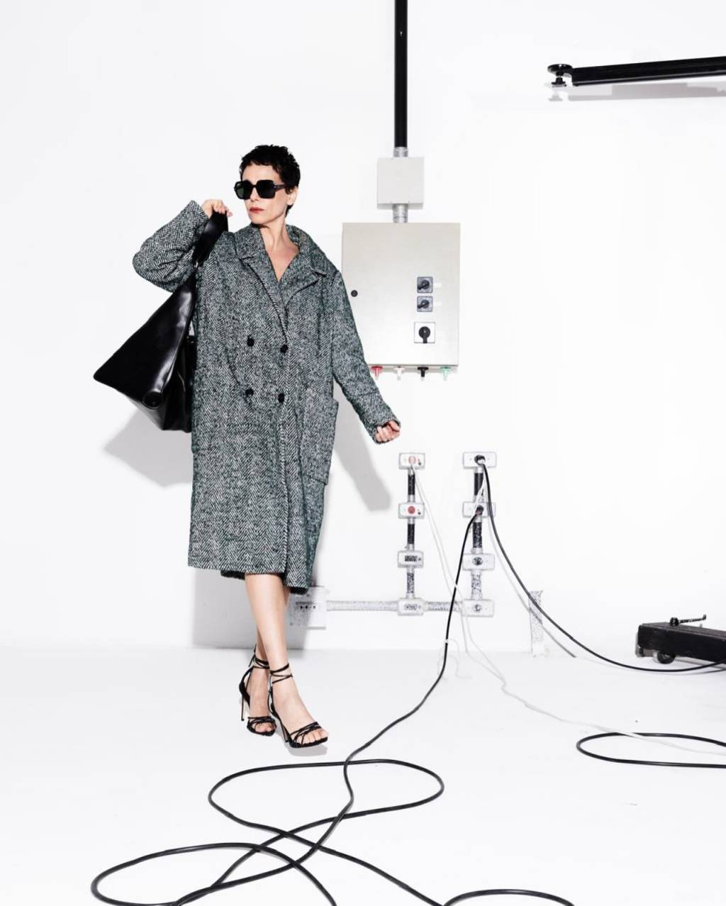look-elegante-malu-galli Foto de Malu Galli usando um look composto por trench coat cinza, bolsa preta longa, óculos de sol pteto e salto preto