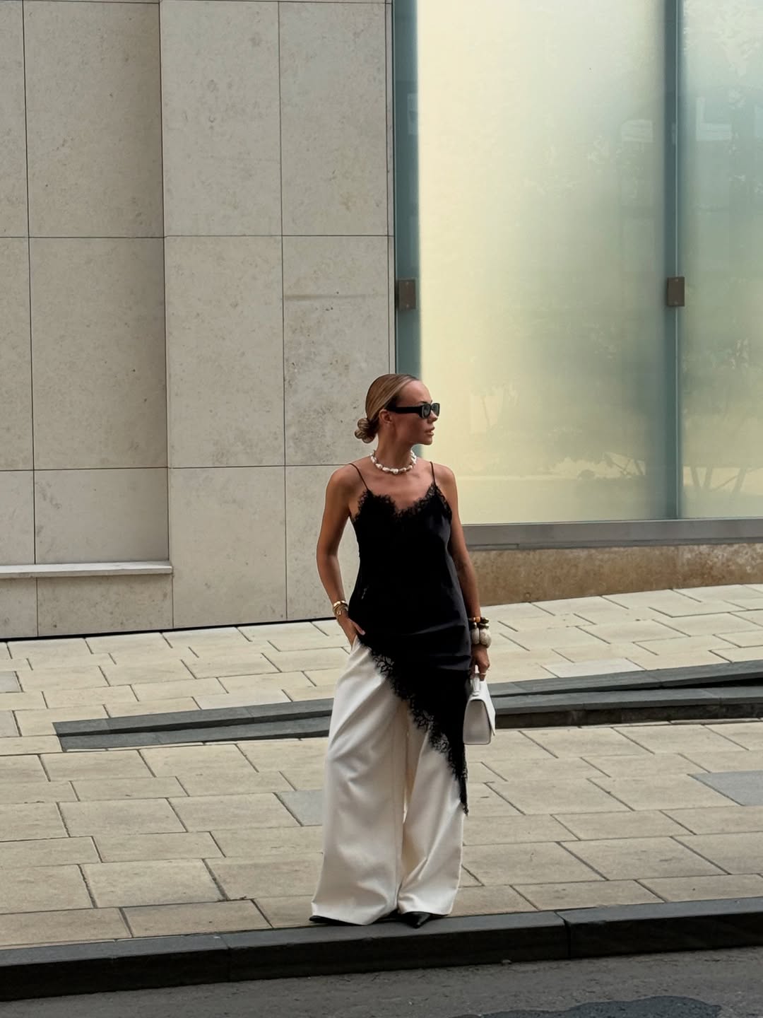 Vestido preto de renda sobre calça branca ampla em look moderno