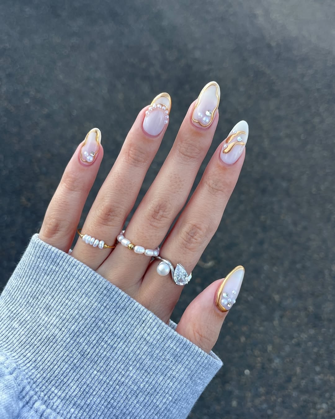 Foto de uma mão com as unhas amendoadas coloridas por uma unha delicada e elementos em 3D