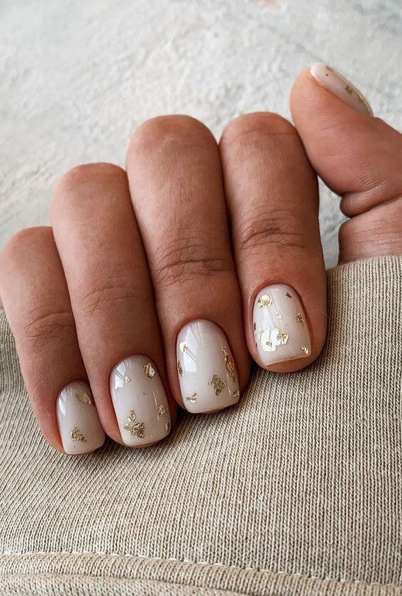 Aplicações douradas transformam as unhas brancas em um visual sofisticado