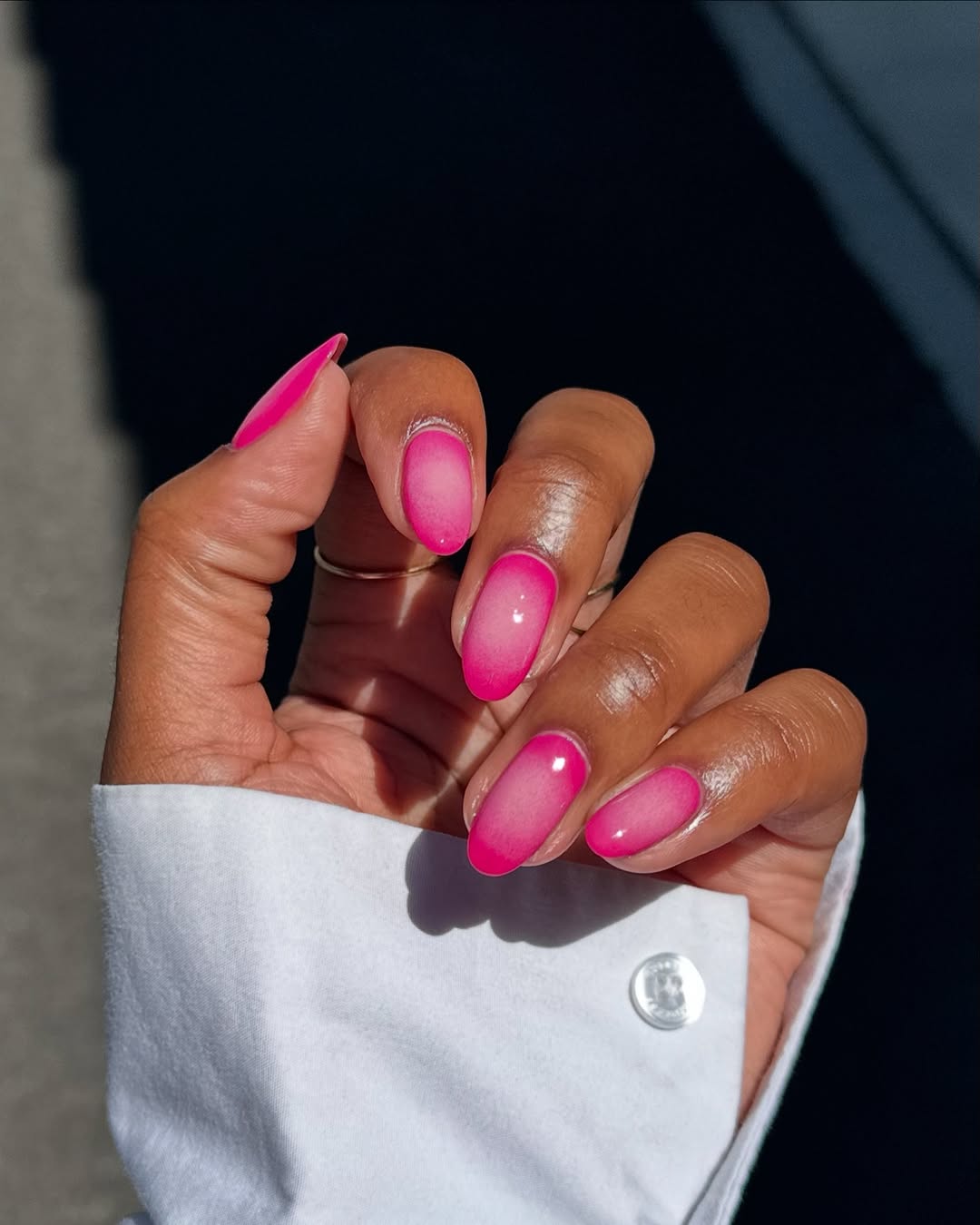 Foto de uma mão com as unhas amendoadas coloridas de rosa