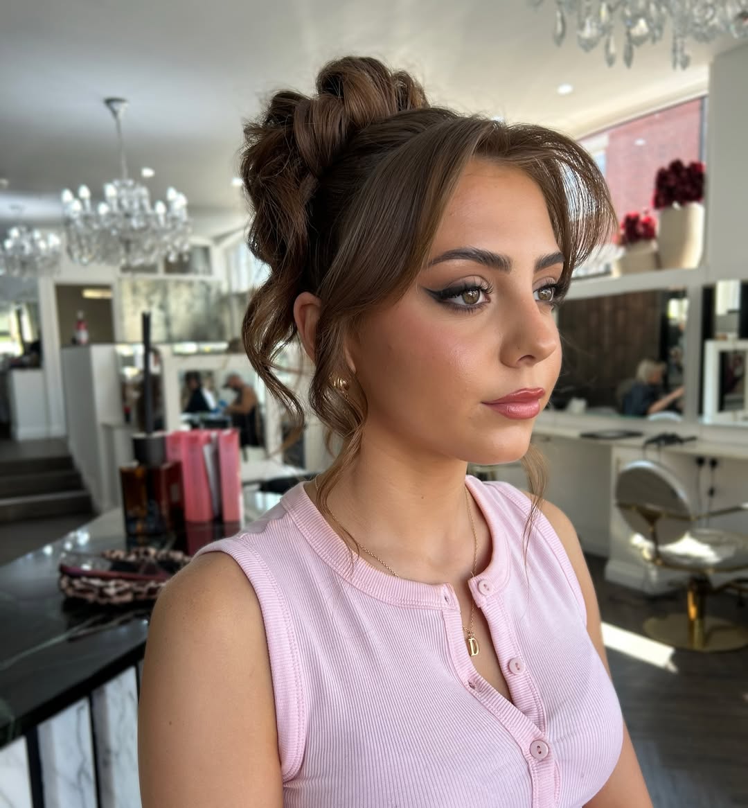 Coque alto com tran&ccedil;a frontal e mechas soltas para formatura