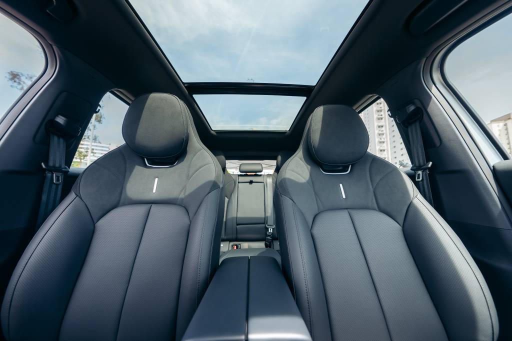 Interior frontal do Omoda 7 com dois bancos dianteiros esportivos em tom grafite e teto solar panorâmico aberto, deixando o habitáculo iluminado