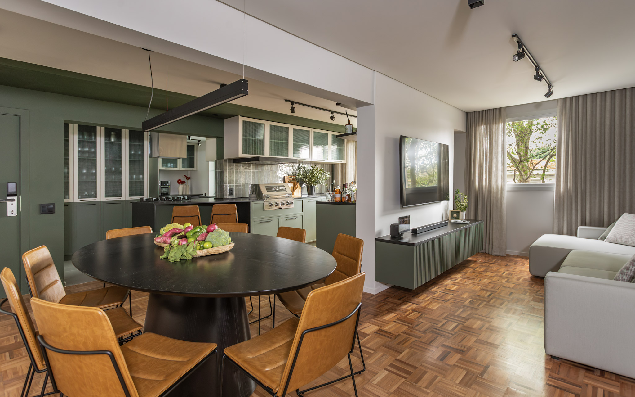 Sala de estar, tv e cozinha integradas com ch&atilde;o de taco. M&oacute;veis em cores de madeira e verde musgo