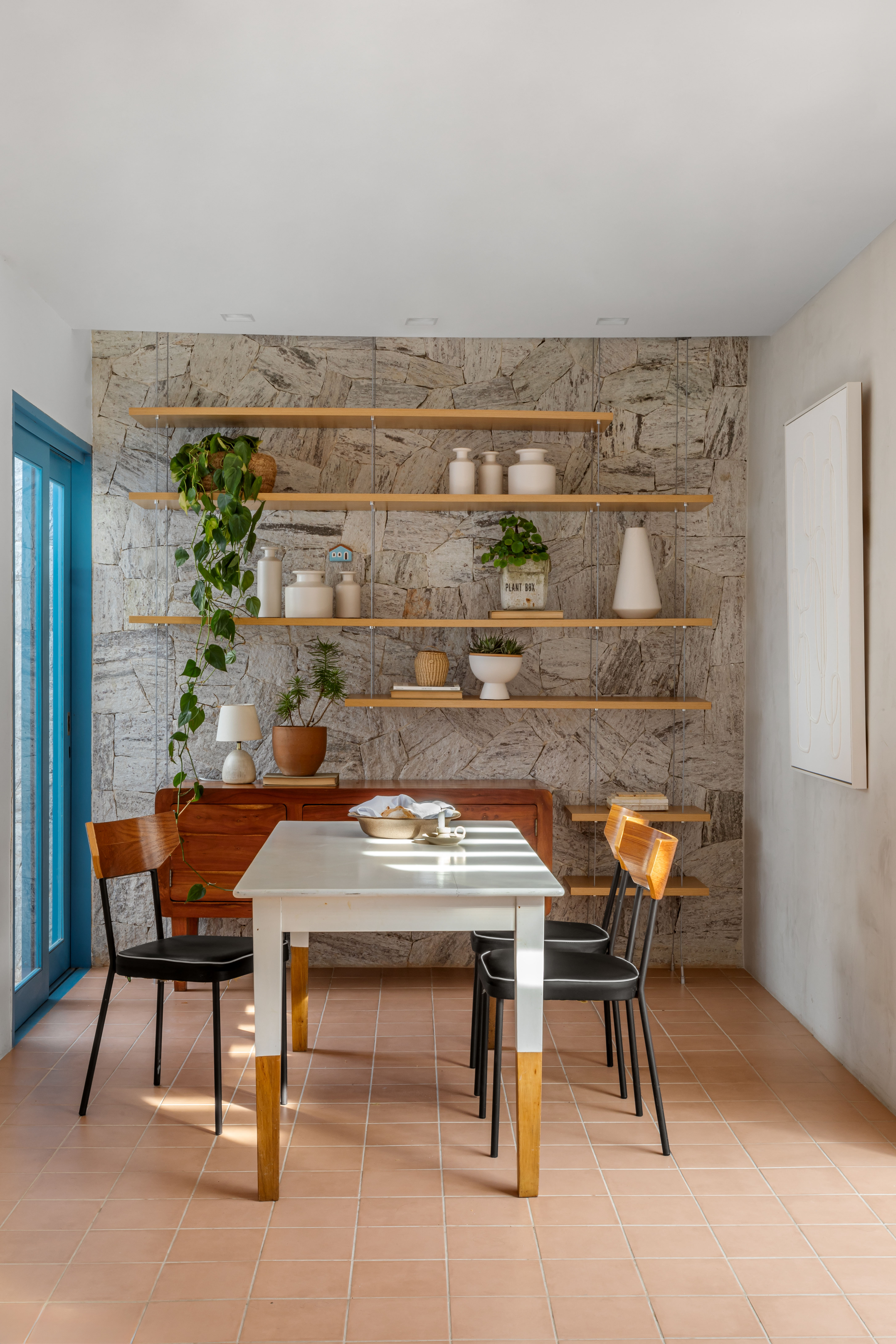 Sala de jantar com piso terracota e mesa branca no centro.