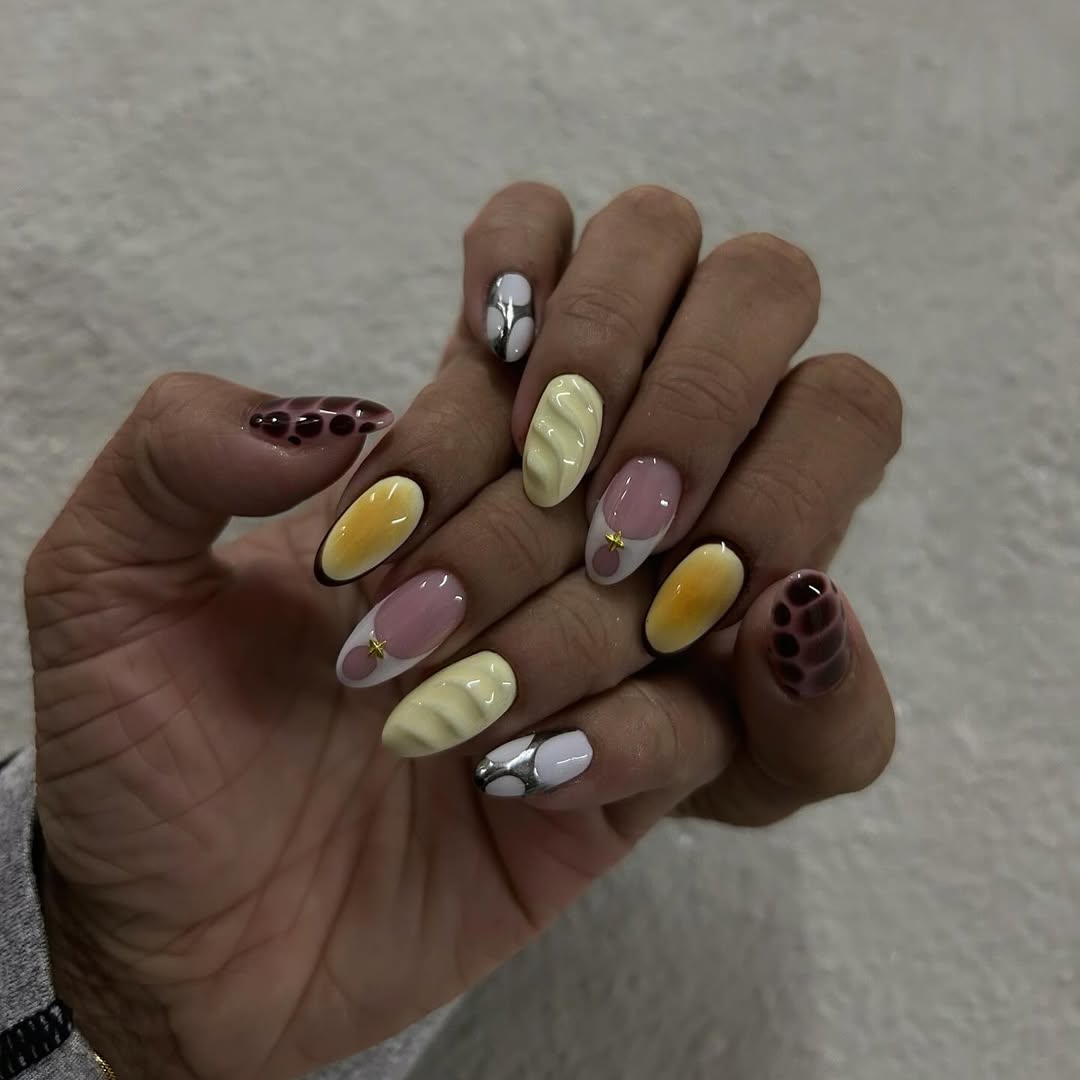Unhas acrigel em tons de amarelo e marrom com textura e acabamento espelhado
