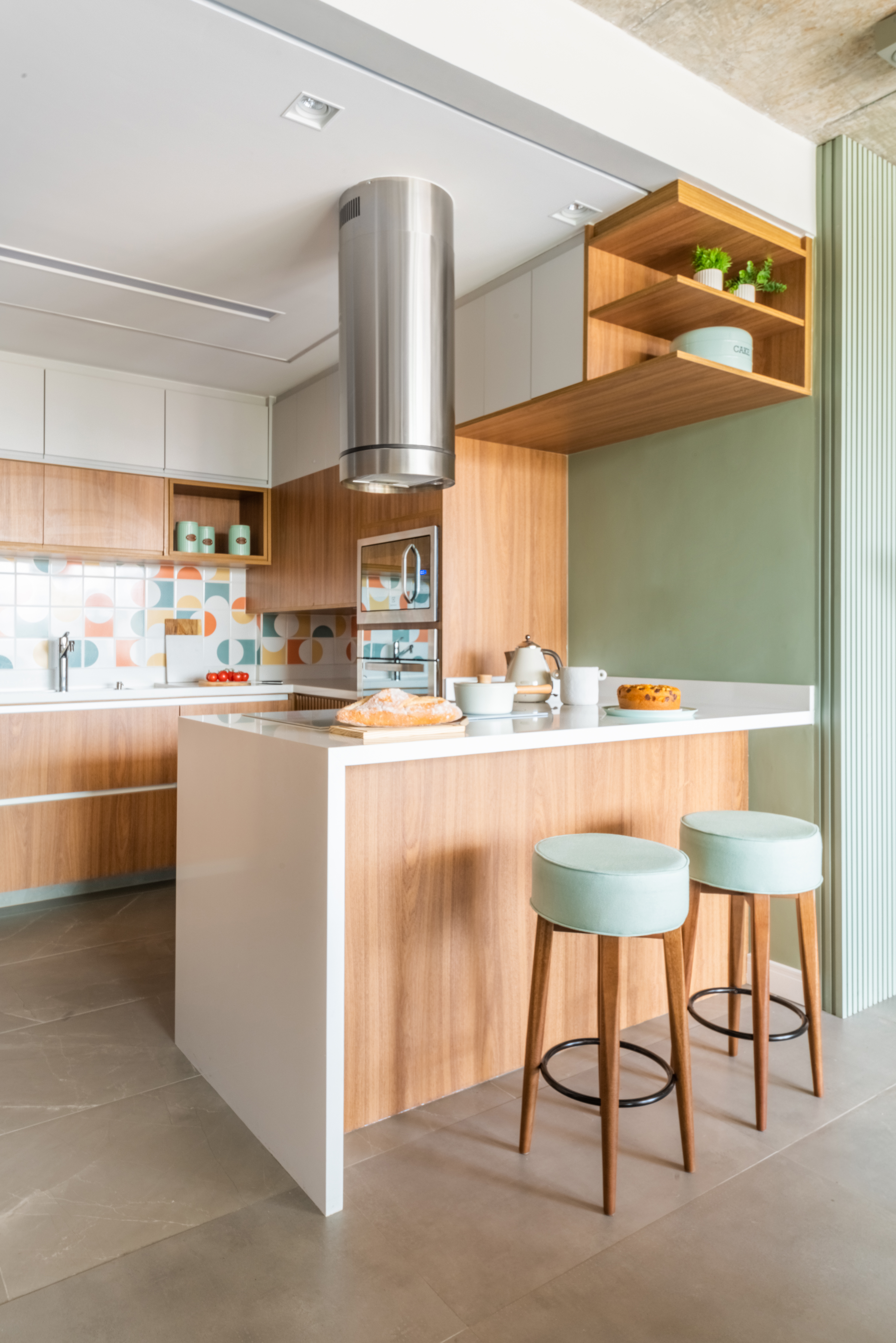 Cozinha americana pequena com cooktop, detalhes em madeira e parede verde pistache