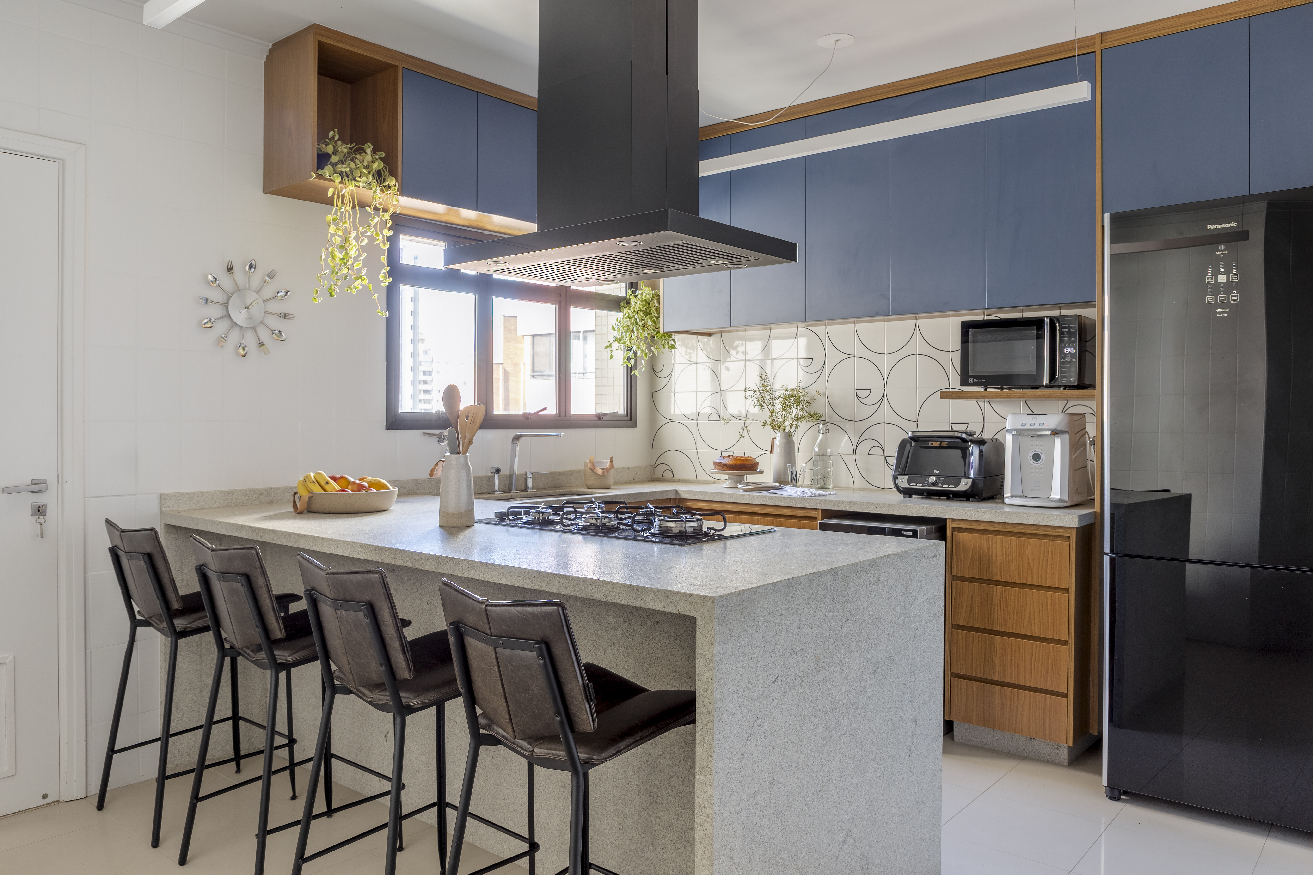 Cozinha americana com cooktop, paredes bancas e azuis, geladeira moderna preta