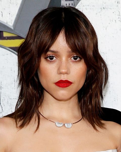 Close de mulher de cabelo castanho escuro repicado usando batom vermelho