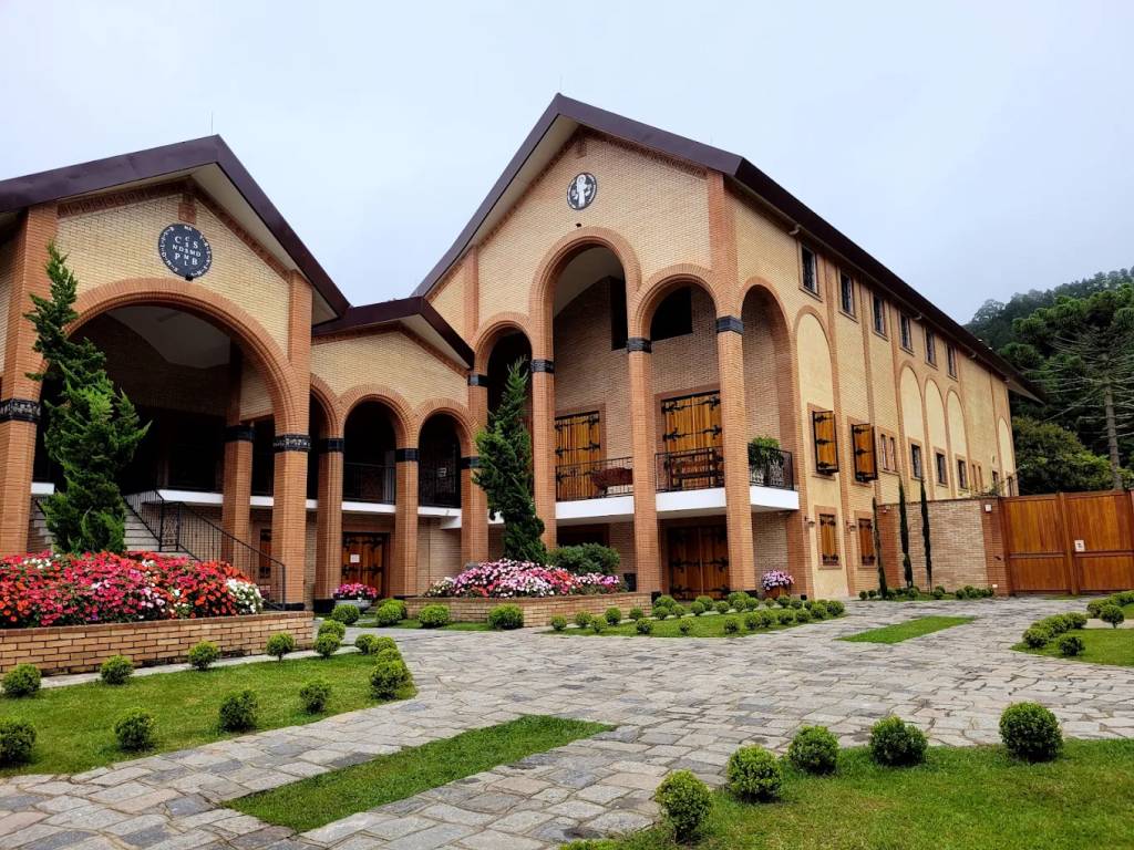 Mosteiro visto de fora com arquitetura clássica monástica e tijolos aparentes.
