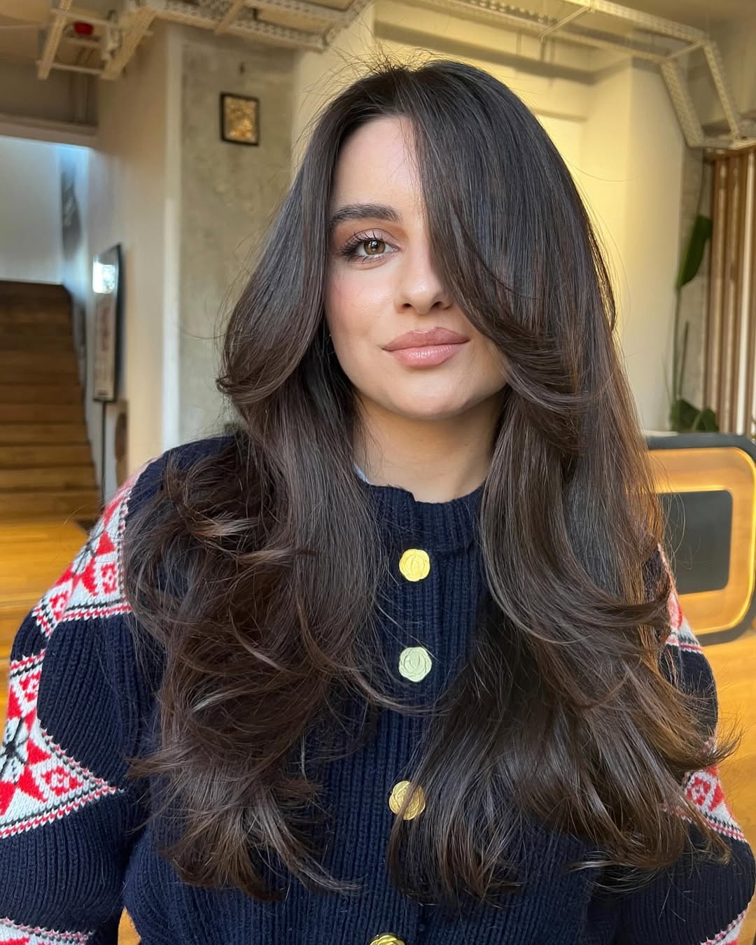Foto de uma mulher branca usando um cabelo longo com o corte em camadas. As pontas do cabelo s&atilde;o onduladas
