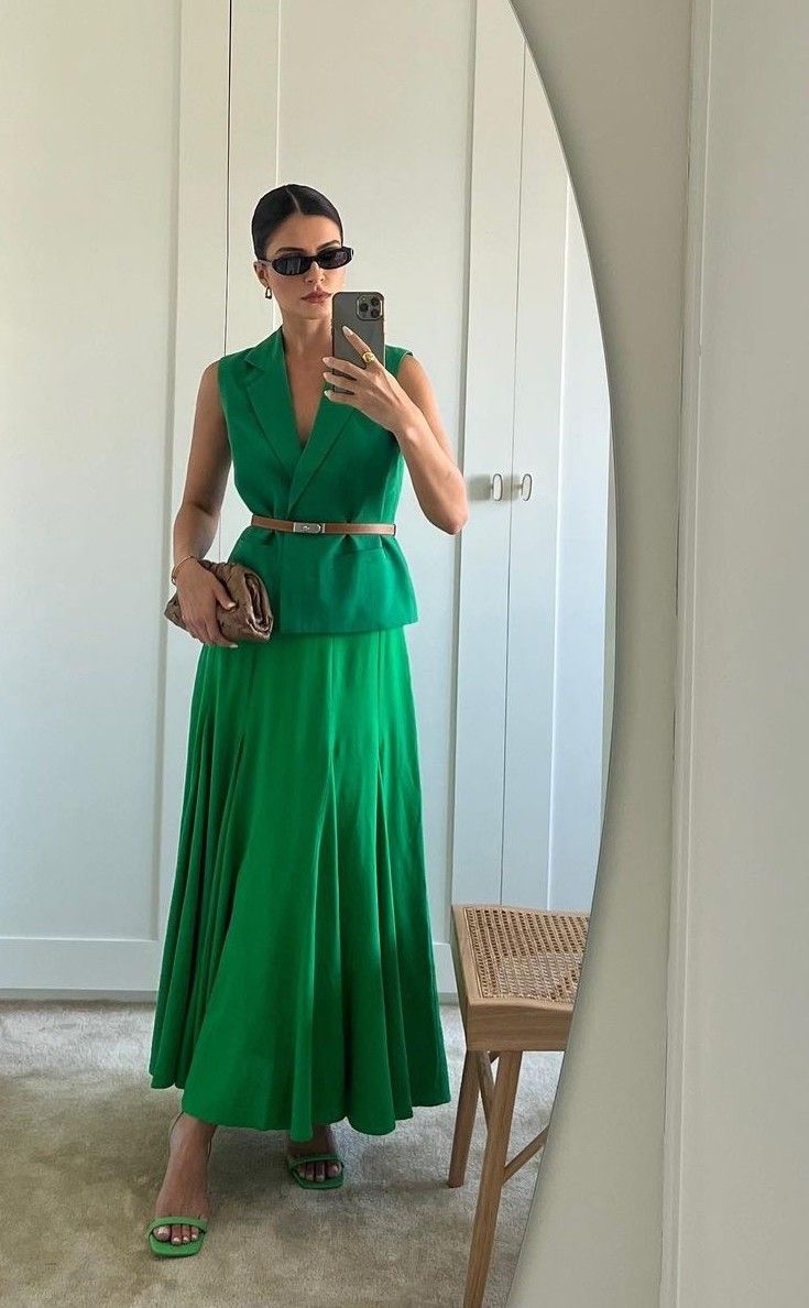 Foto de uma mulher usando um look composto por regata verde, saia longa verde e &oacute;culos de sol