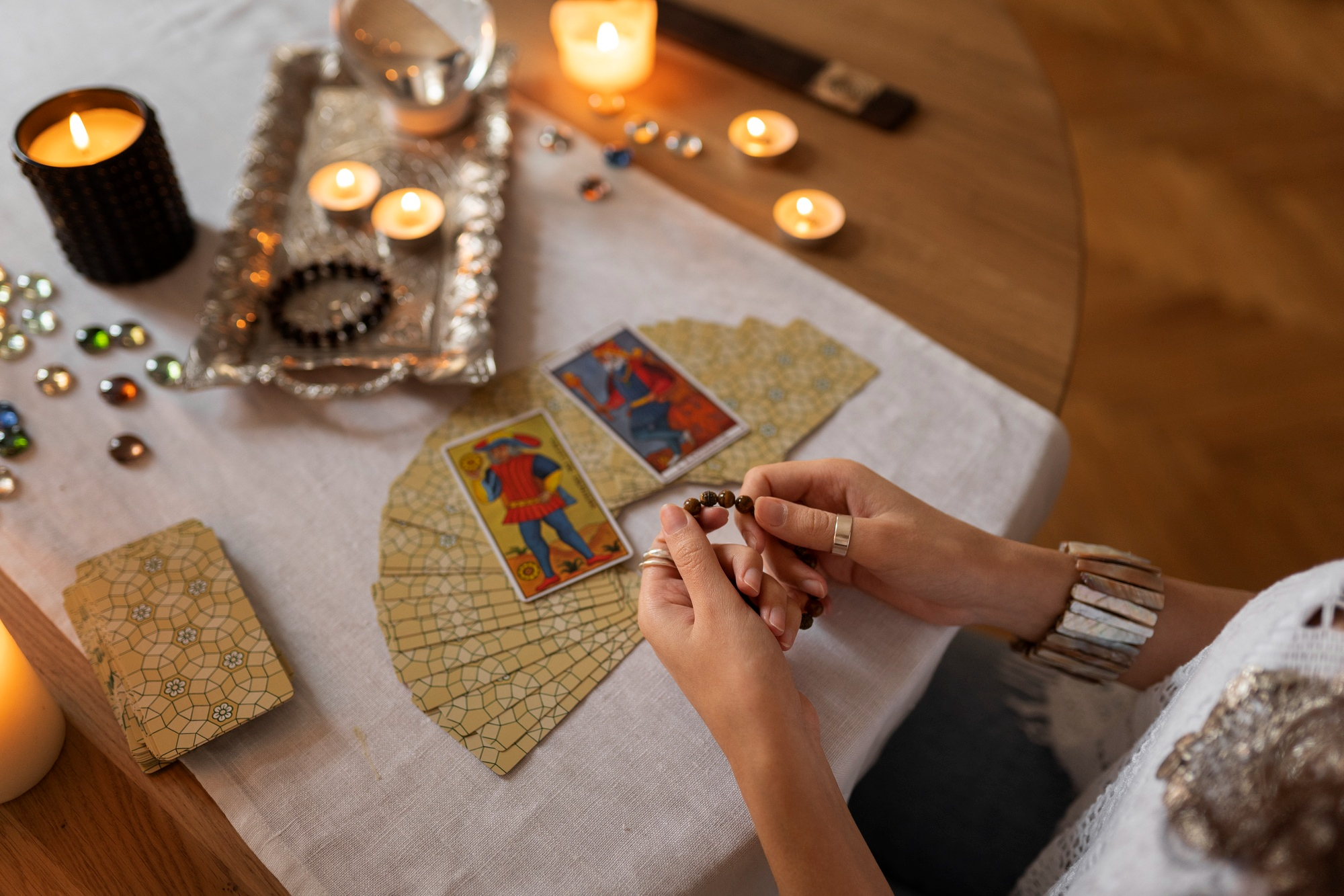 Leitura de Tarô com cartas abertas sobre mesa decorada com velas e cristais, representando o clima espiritual de janeiro de 2026 sob a regência de A Imperatriz; ritual de autocuidado, intuição e energia de criação, prosperidade e conexão emocional no começo do ano