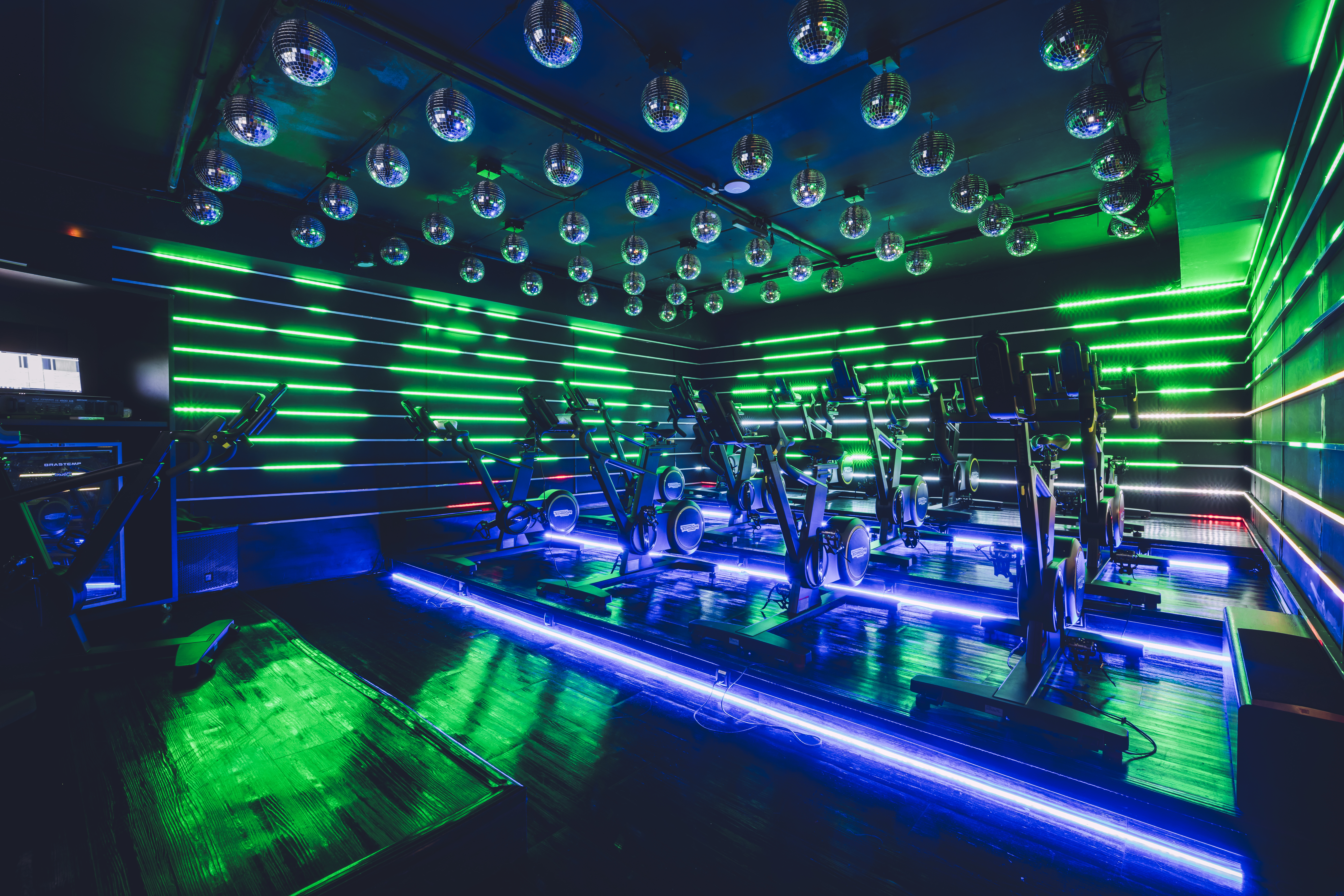 Sala de spinning com globos espelhados e luzes verde e azul