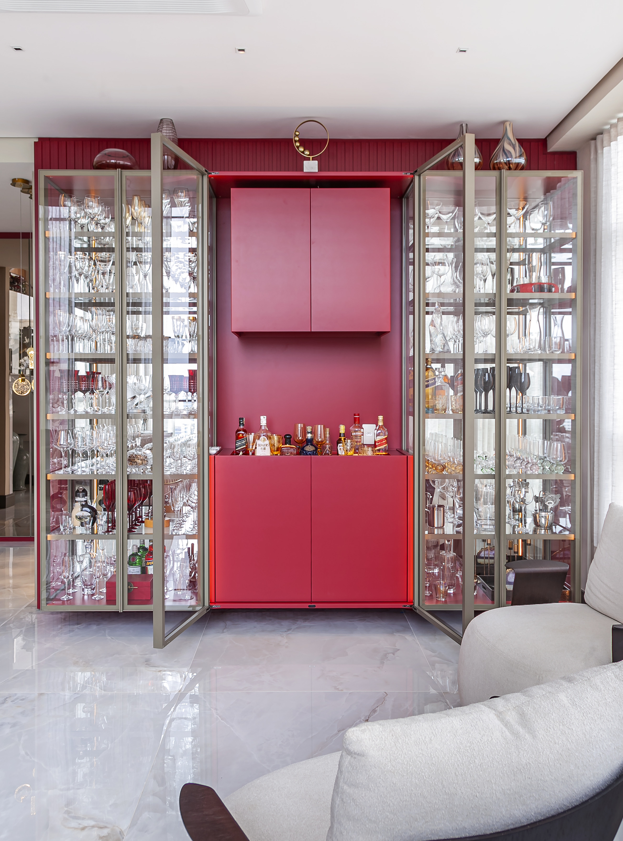Cristaleira vermelha com bar ao centro envolta por arm&aacute;rios envidra&ccedil;ados