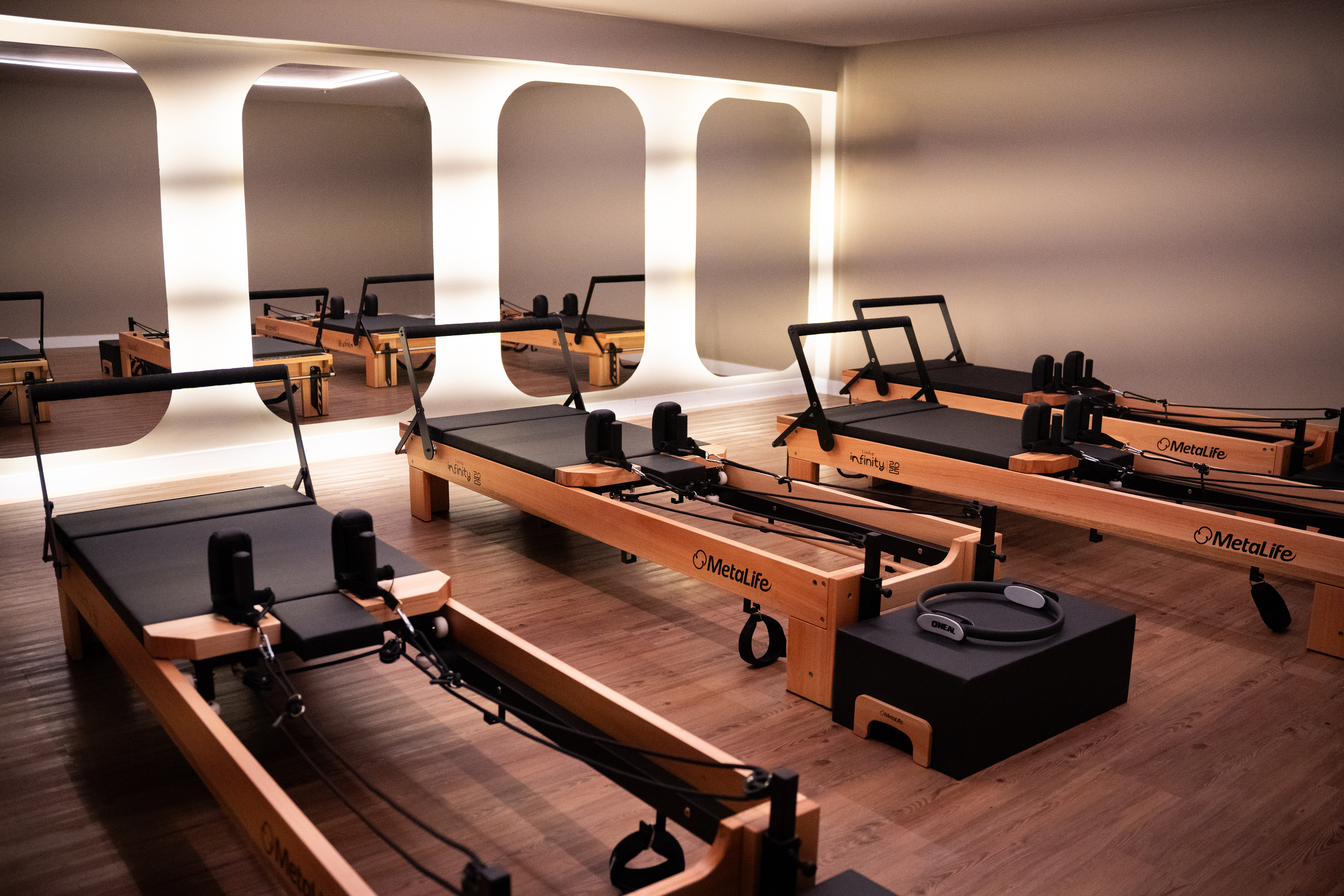 Sala de pilates com quatro espelhos e parede iluminada
