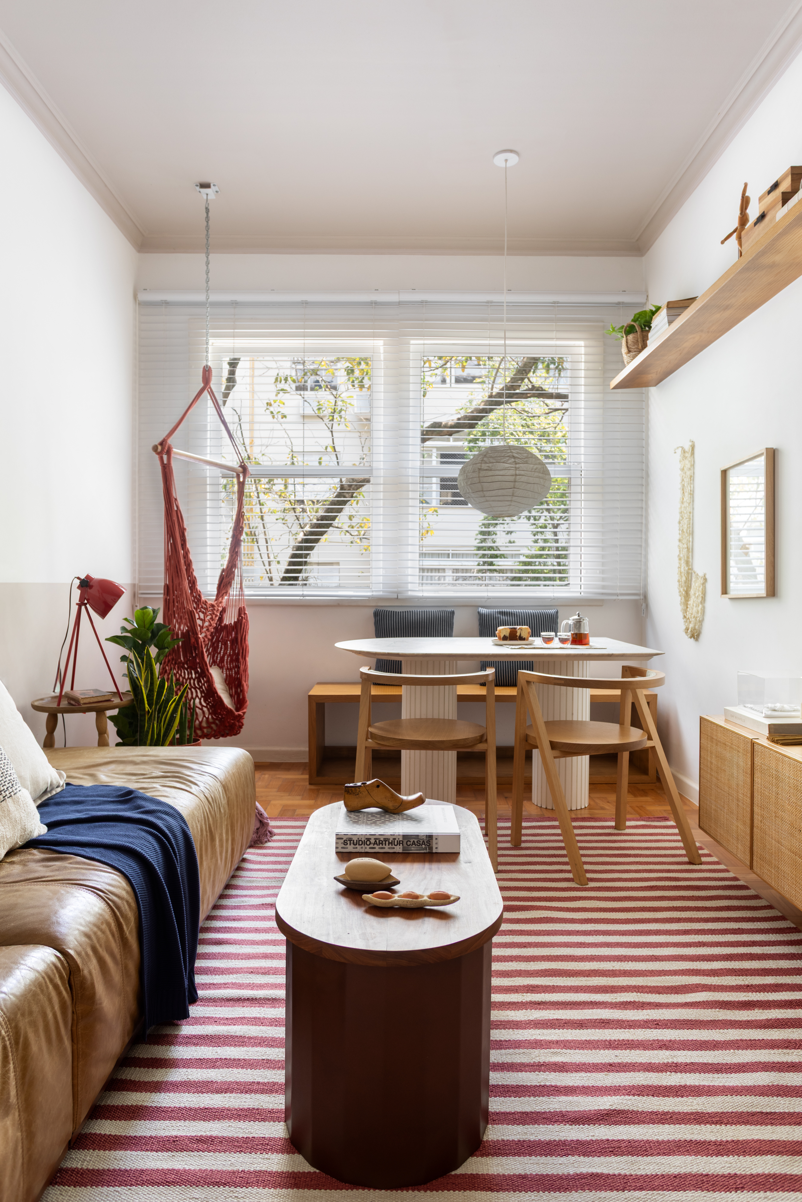 Sala de TV integrada com mesa de jantar com vista para &aacute;rvores e rede de descanso