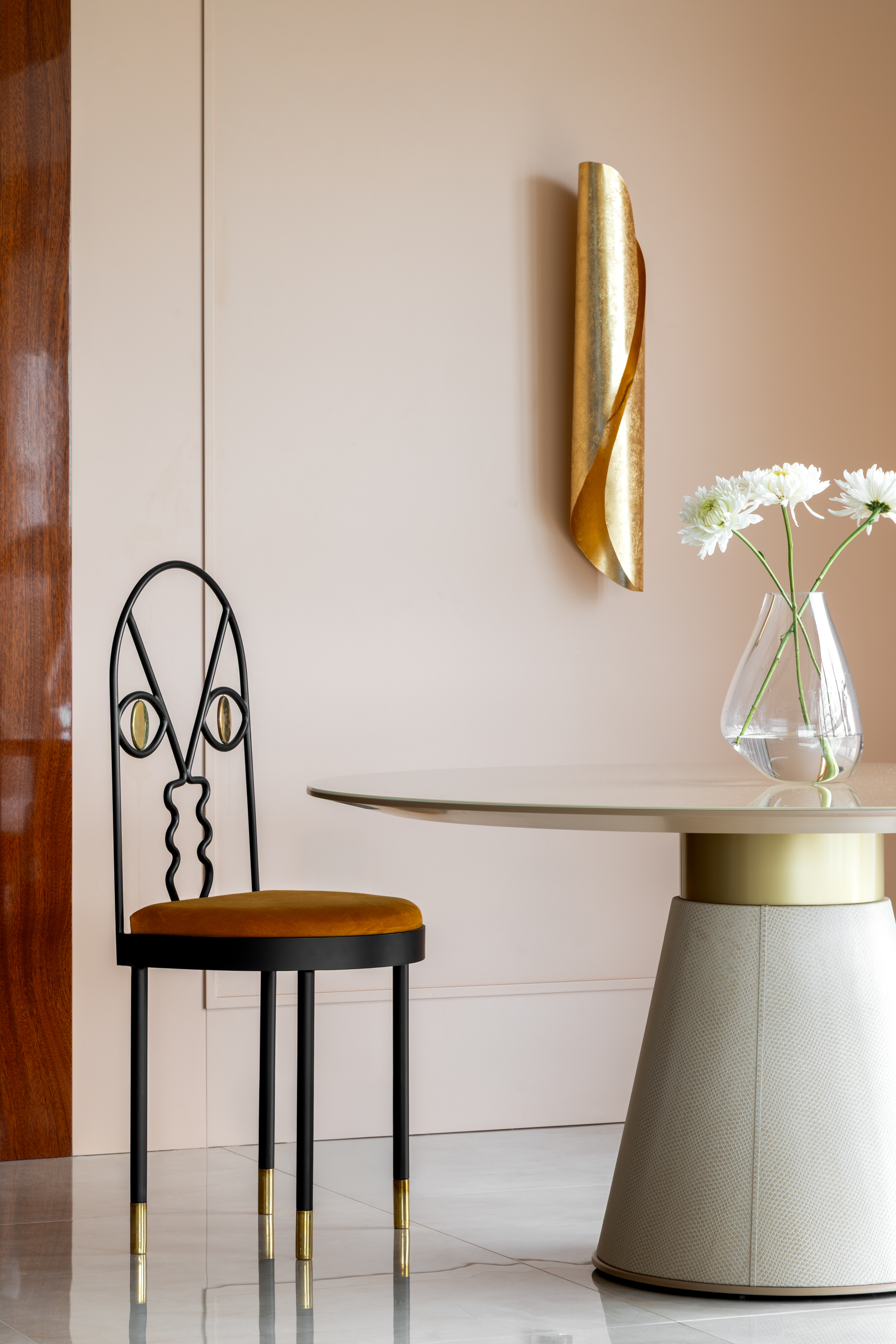 Sala de estar com mesa de centro com vaso de flores, lumin&aacute;ria dourada e cadeira ao lado