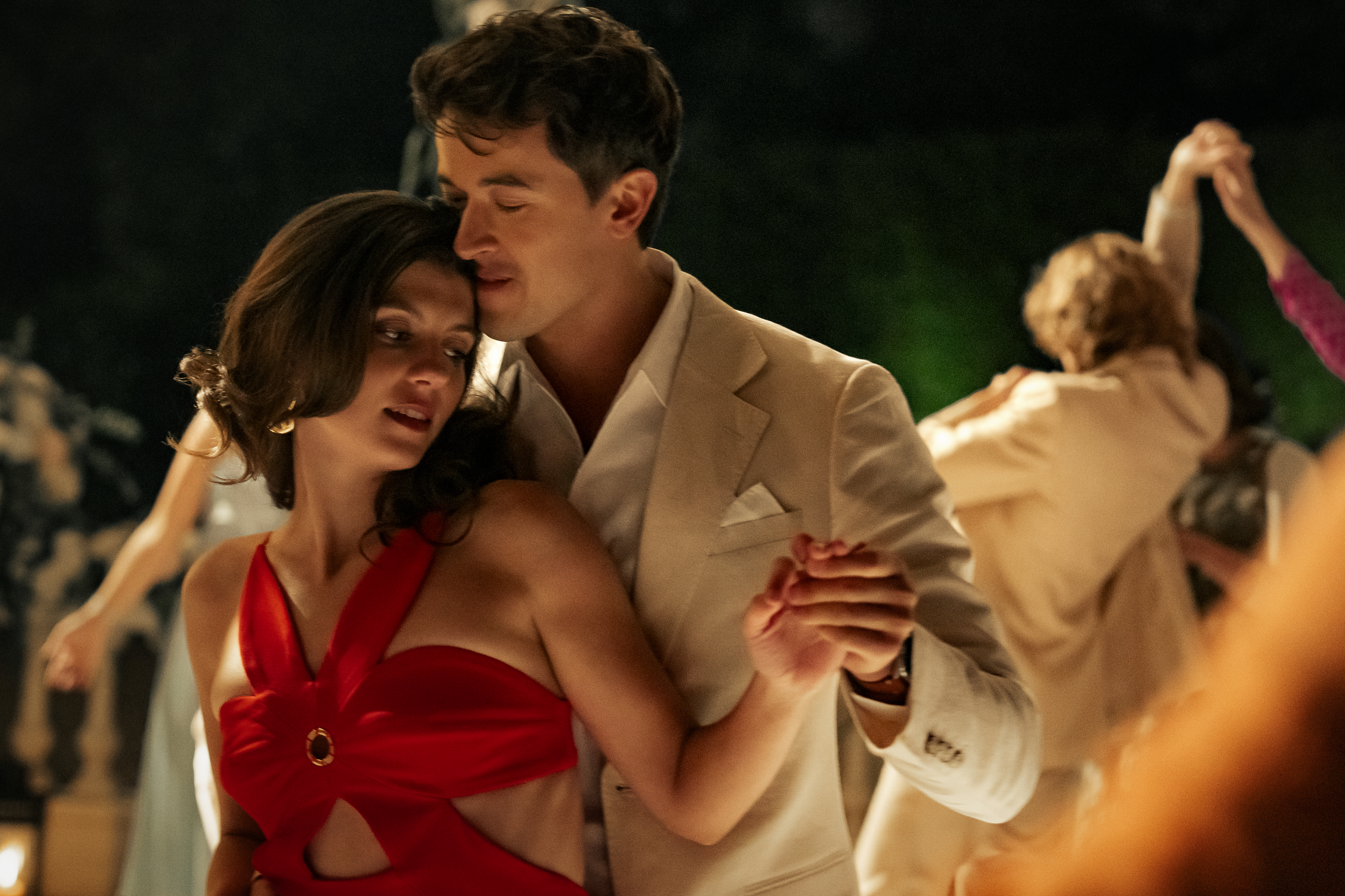 Poppy e Alex dan&ccedil;am juntos em evento noturno, cena rom&acirc;ntica do filme People We Meet on Vacation da Netflix, baseado no best-seller de Emily Henry e comparado a When Harry Met Sally por retratar amor entre amigos.