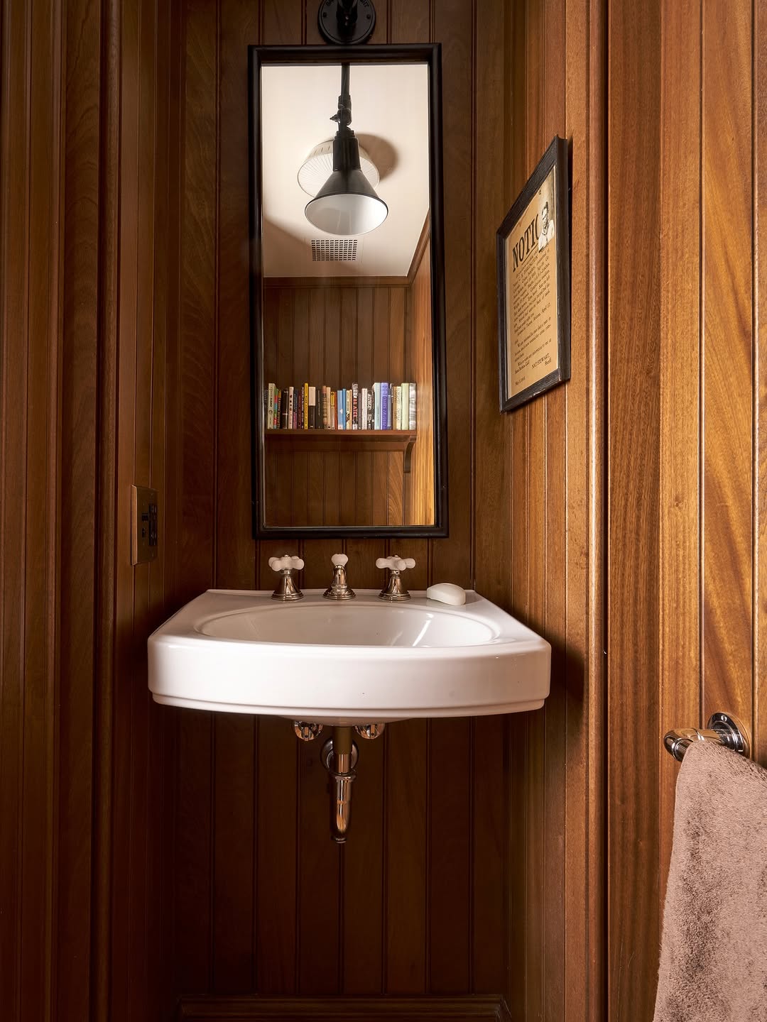 Lavabo vintade com paredes de madeira com pagina&ccedil;&atilde;o vertical e livros em prateleira