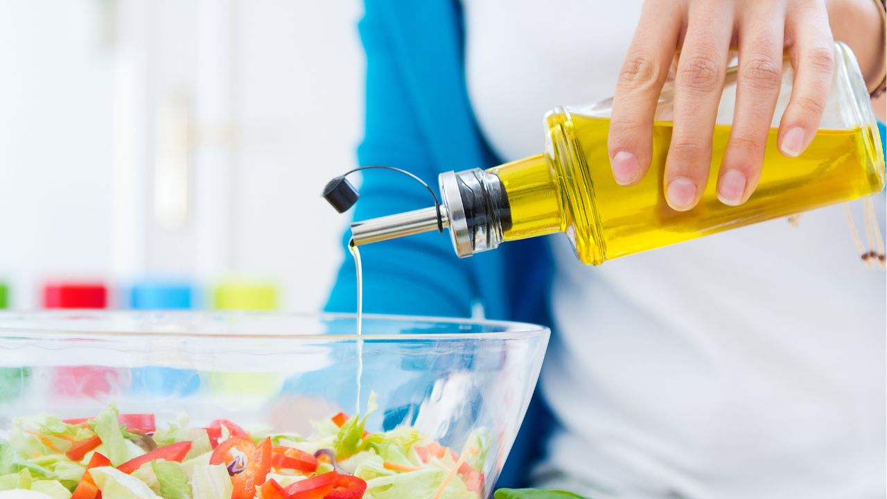 Close em pessoa colocando azeite em pote de salada