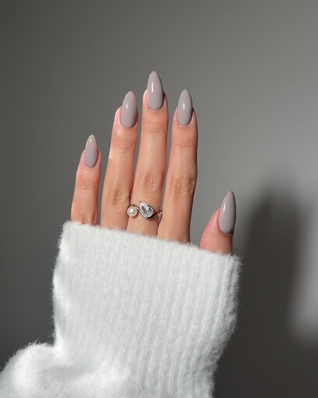 Foto de uma m&atilde;o com unhas coloridas de cinza