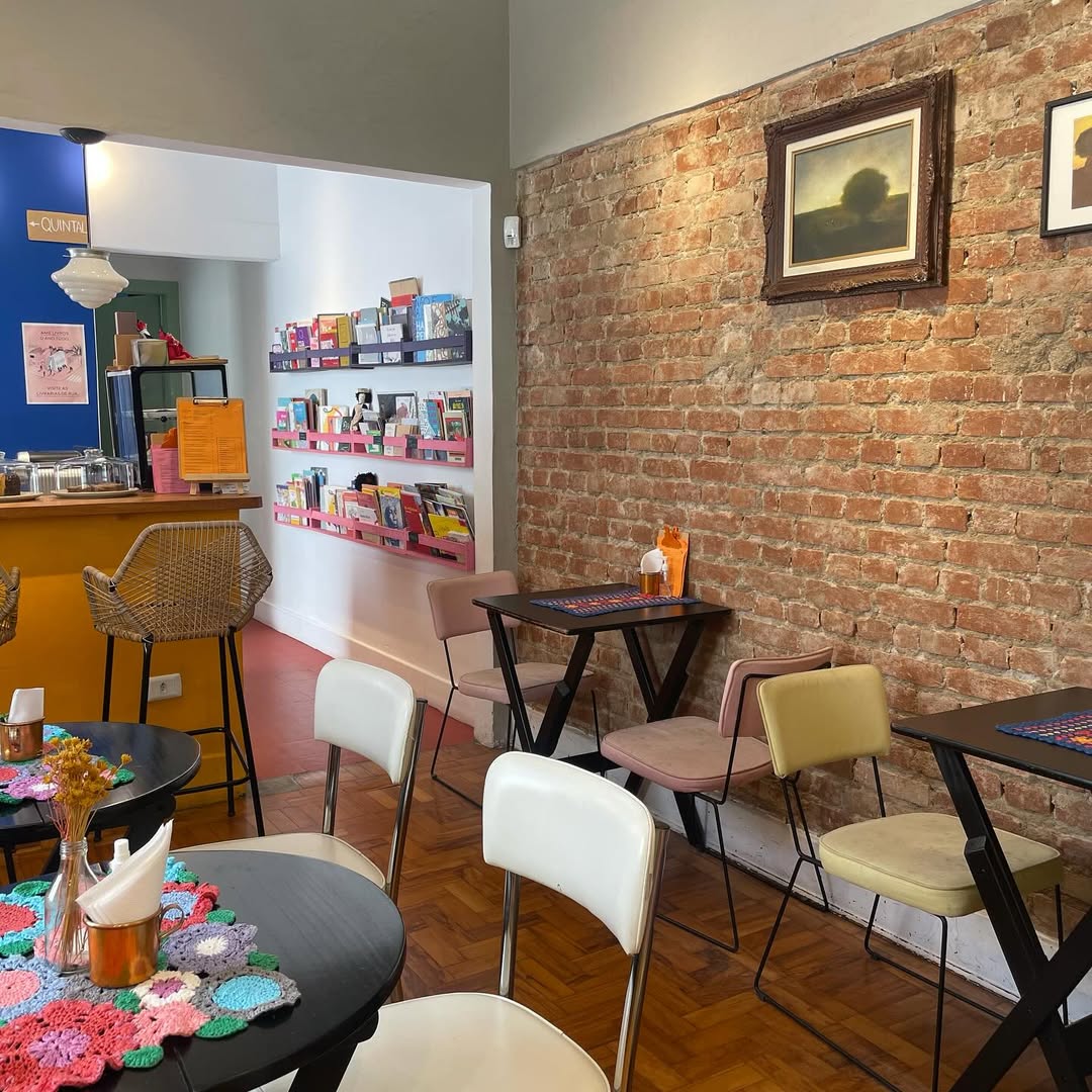 Cantinho de leitura da Livraria Mi&uacute;da com cadeiras aconchegantes e livros infantis organizados para intera&ccedil;&atilde;o familiar.