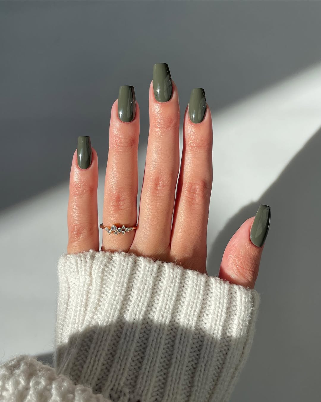 Foto de uma m&atilde;o com unhas coloridas de verde musgo