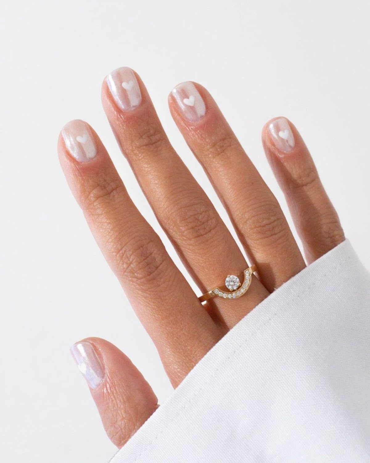Close em m&atilde;o feminina usando branco cintilante com nail art de cora&ccedil;&atilde;o
