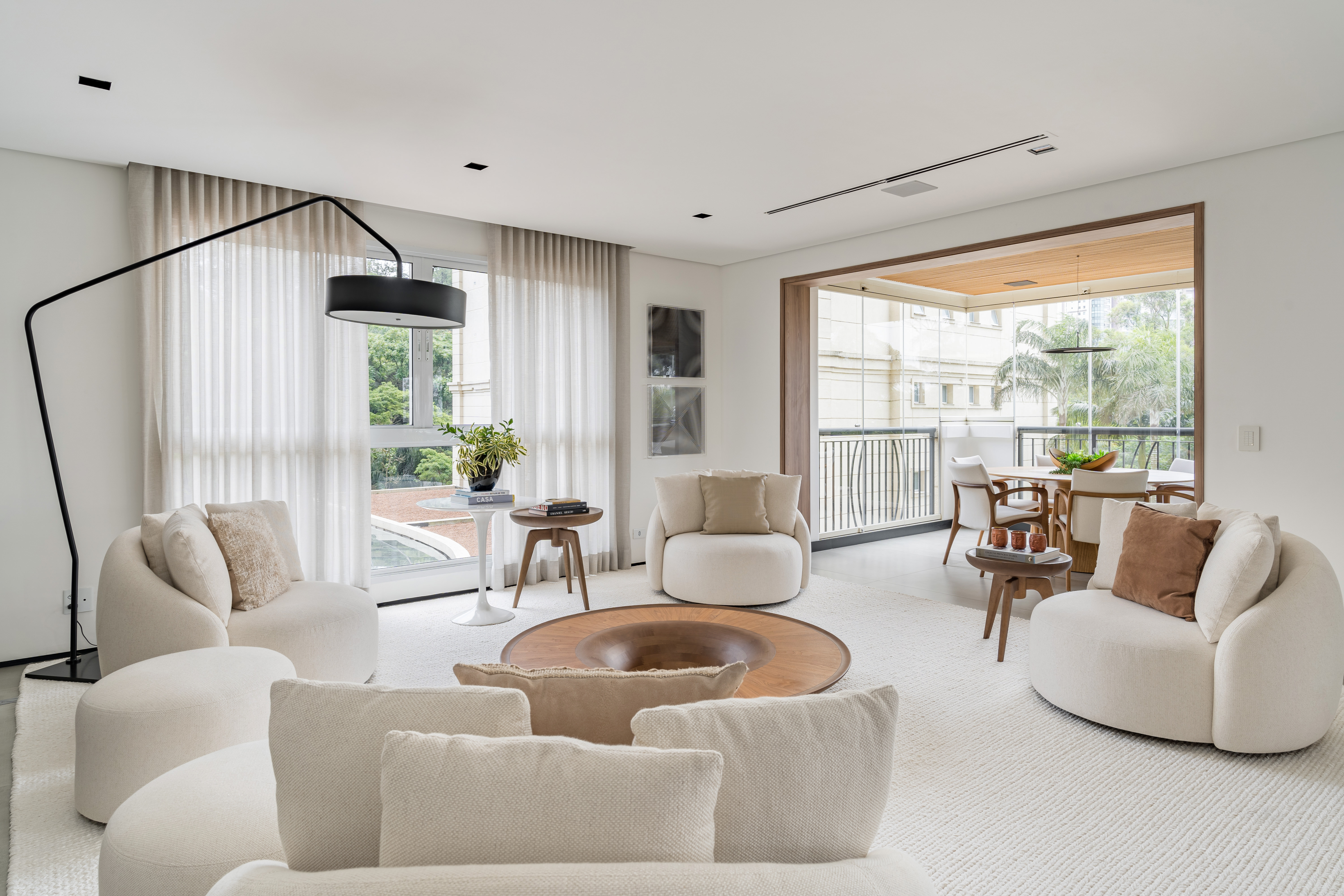 Sala de estar em tons neutros com quatro poltronas em volta de mesa de centro