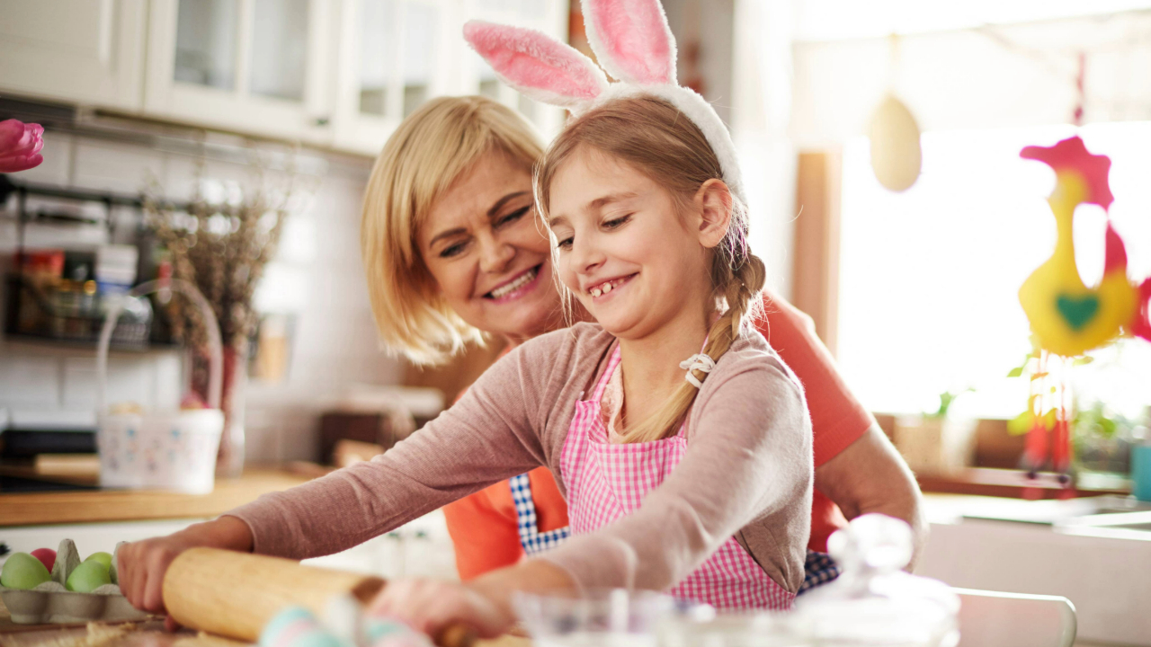 Mãe e criança usando tiara de coelho na cozinha preparando ovos de páscoa